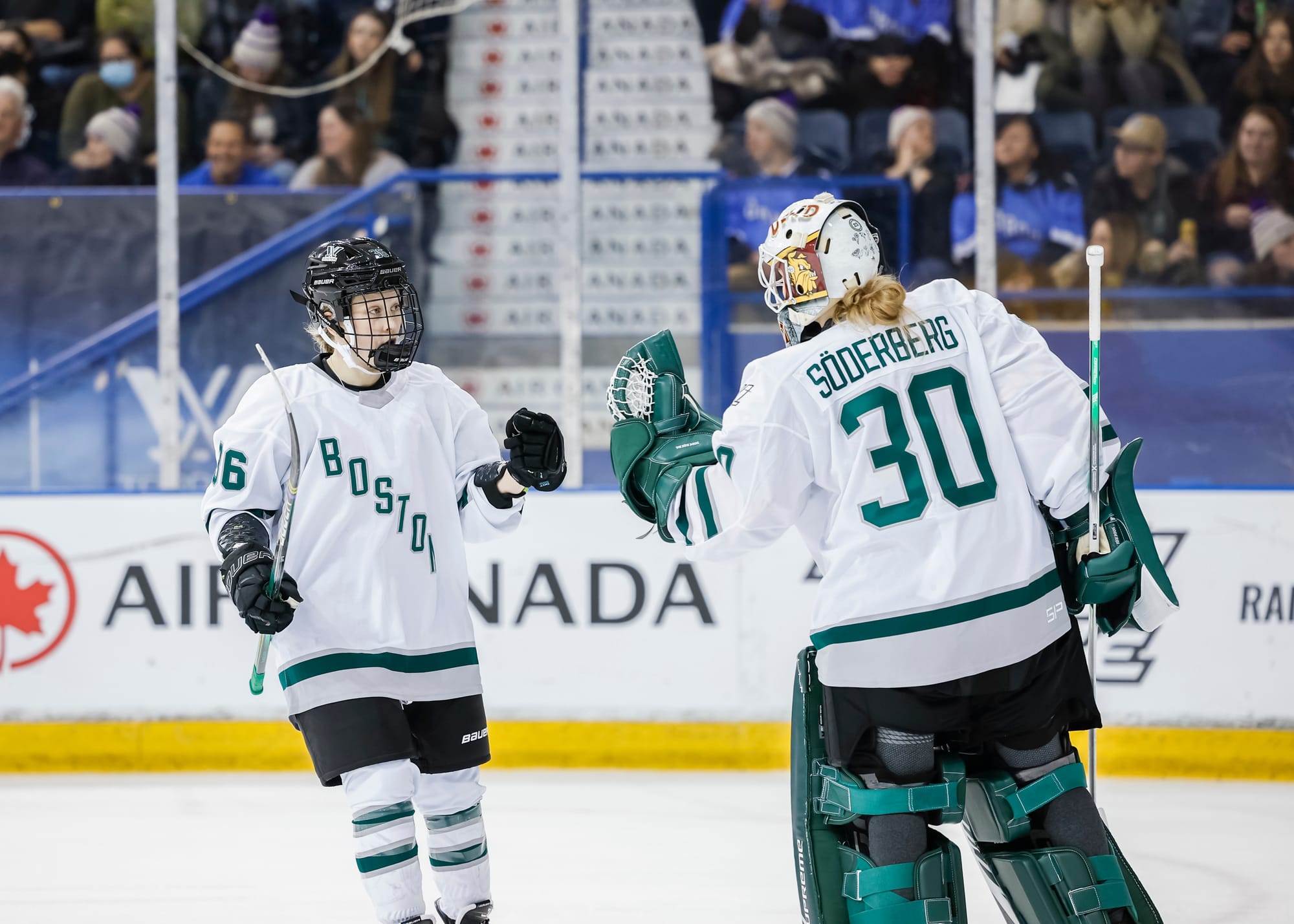 Wearing their white away uniforms, Loren Gabel goes in for a fist bump with Emma Sรถderberg during a game against Toronto.