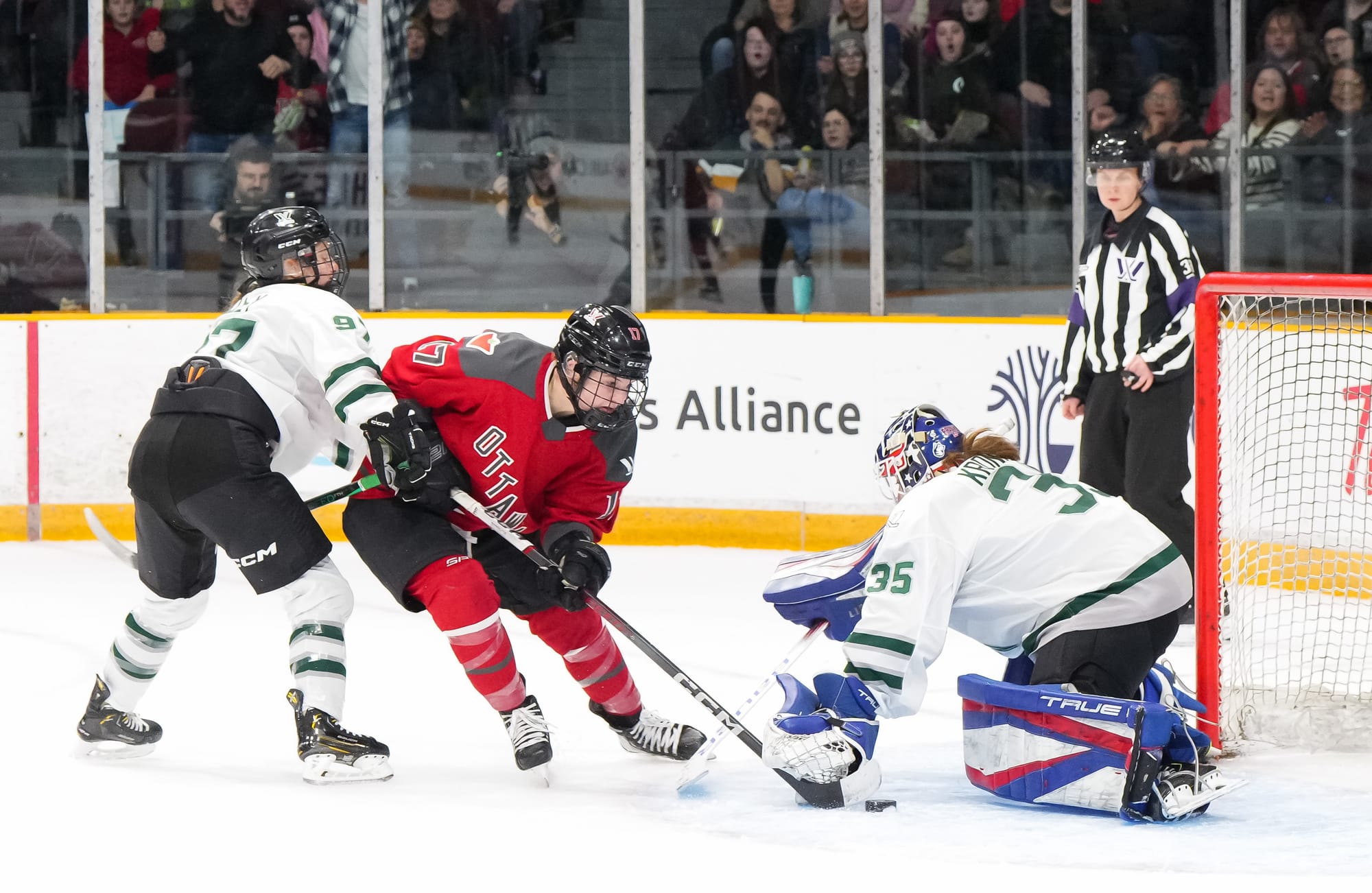 Aerin Frankel, wearing her USA pads and white Boston uniform, makes a save on Gabbie Hughes, wearing red, as Jess Healey, wearing white, defends.
