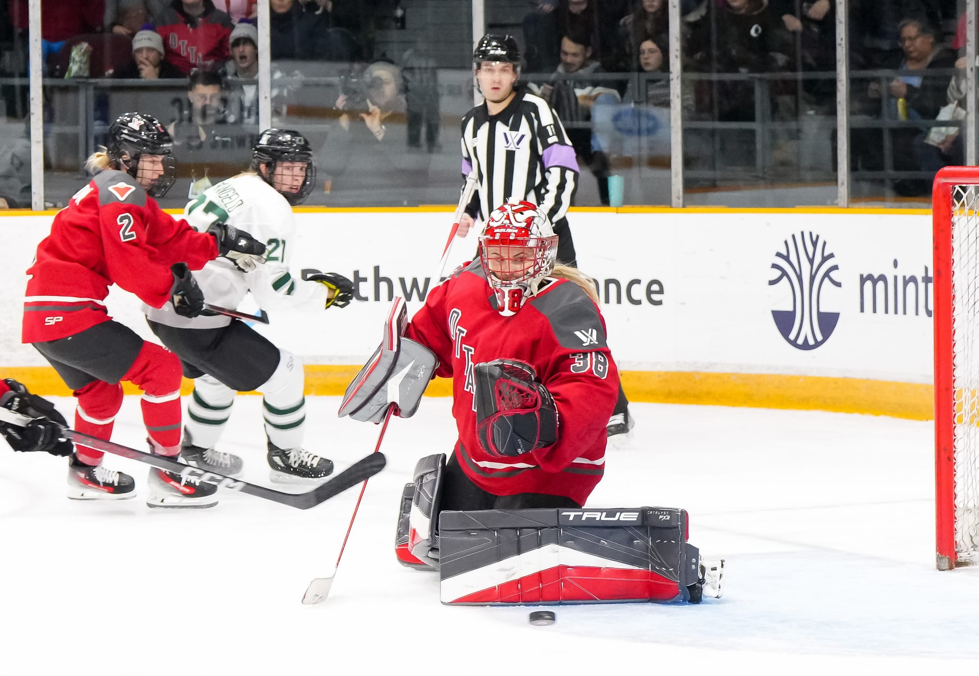 Emerance Maschmeyer, wearing her Ottawa gear and red home uniform, makes a save against Boston.