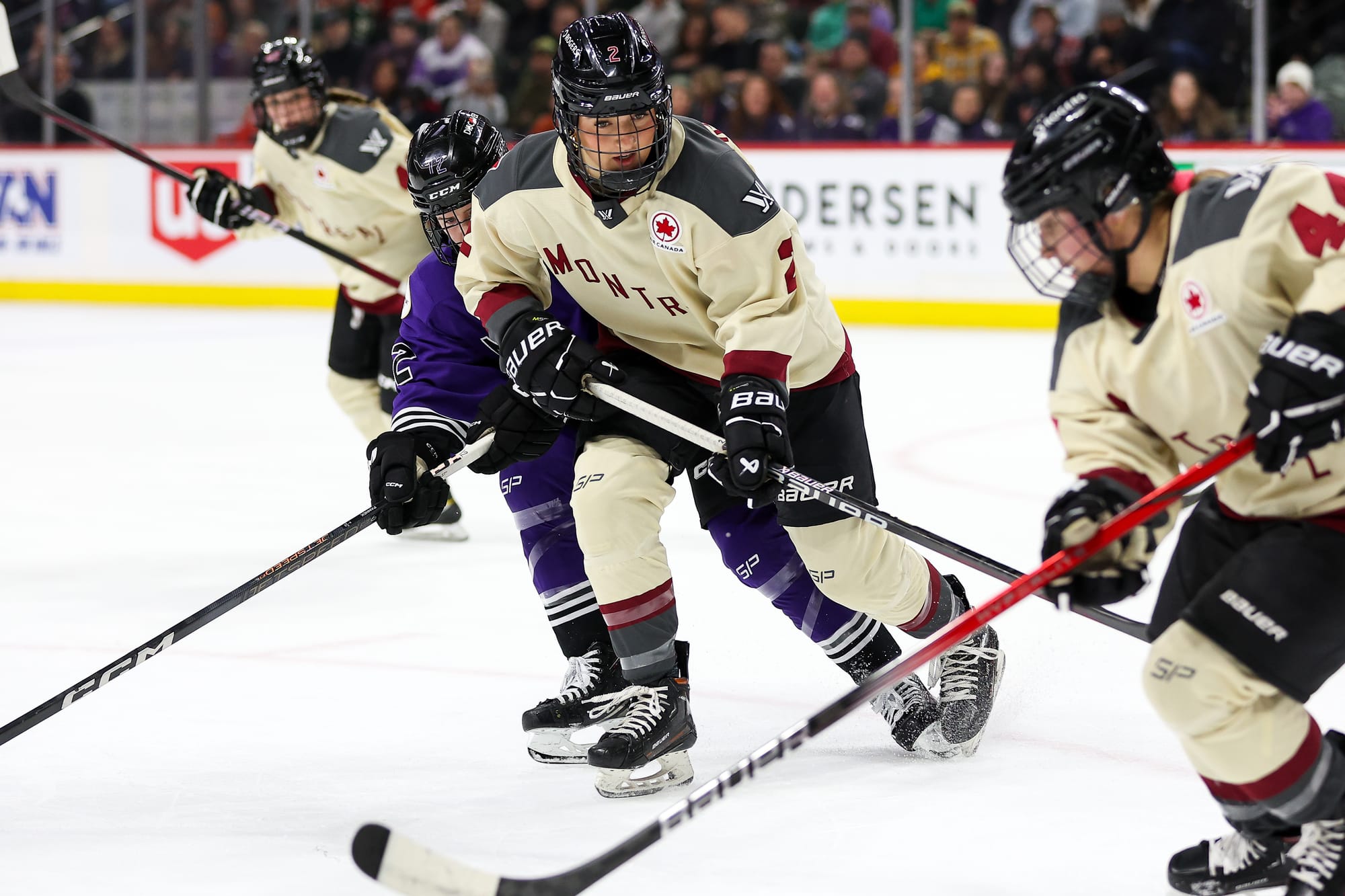 Keopple provides support by blocking a Minnesota defender as Boulier skates with the puck. Both Montrรฉal players are in cream away uniforms.