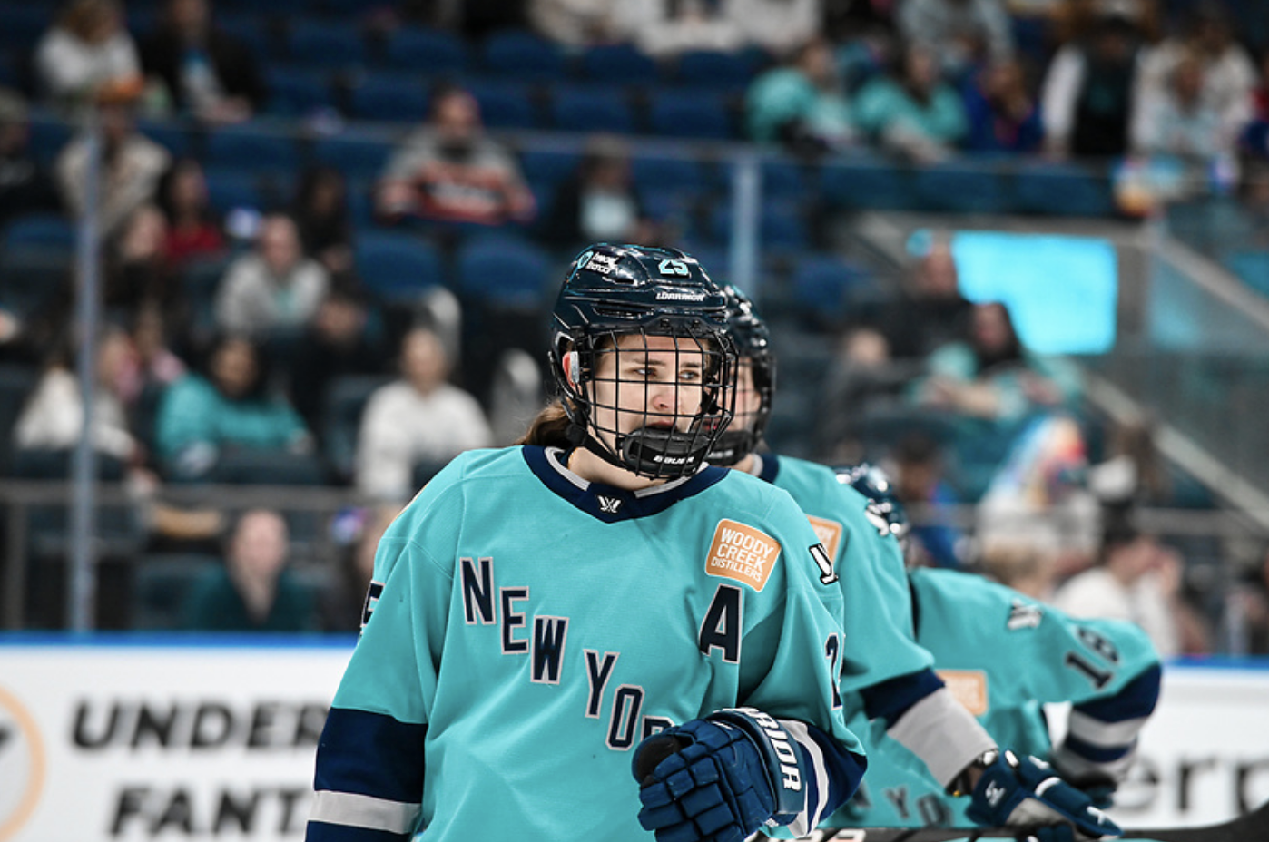 A waist-up shot of Carpenter looking on before a face-off. She is wearing a teal home uniform.