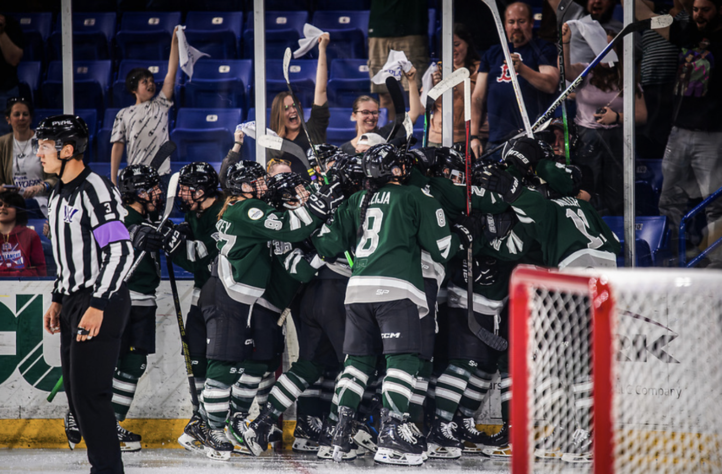 All Boston players celebrate with a big group hug in the corner. They're all wearing green home uniforms.