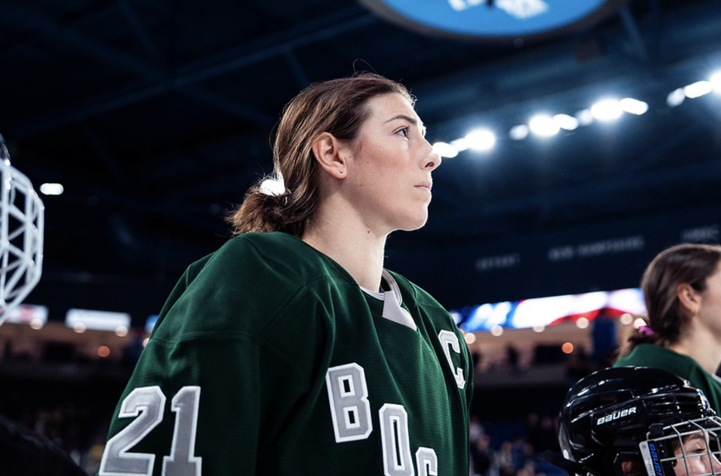 A shoulders-up shot of Knight look up and away from the camera. She has her helmet off and is wearing a green home jersey.