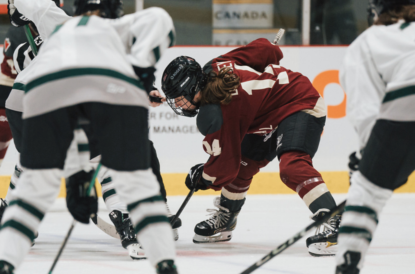 Dempsey, wearing a maroon Montrรฉal uniform, crouches and watches the puck in the referees hand in prepartion for a faceoff.
