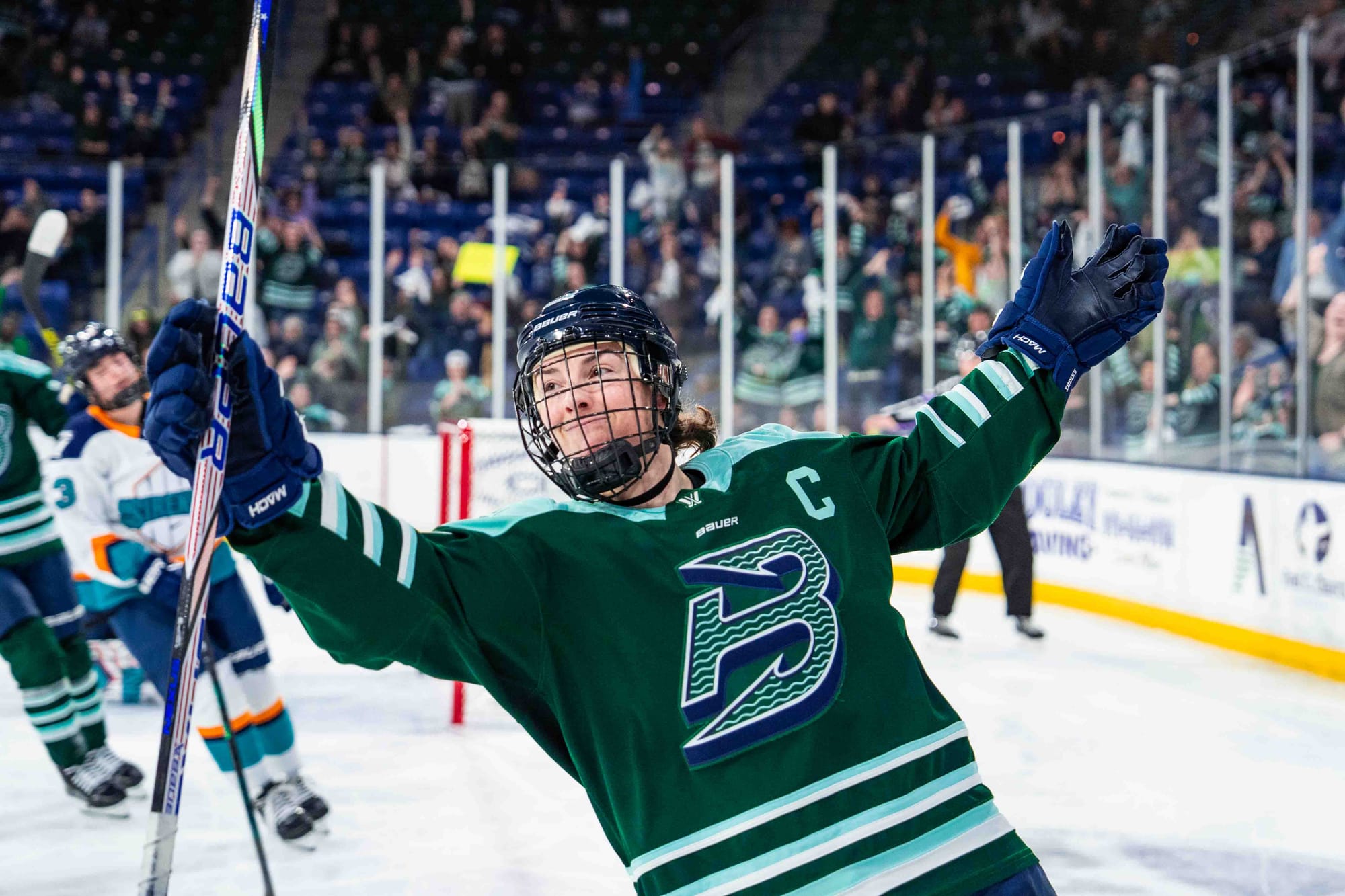 Knight smiles and raises her open arms in celebration. She is wearing a green home uniform.