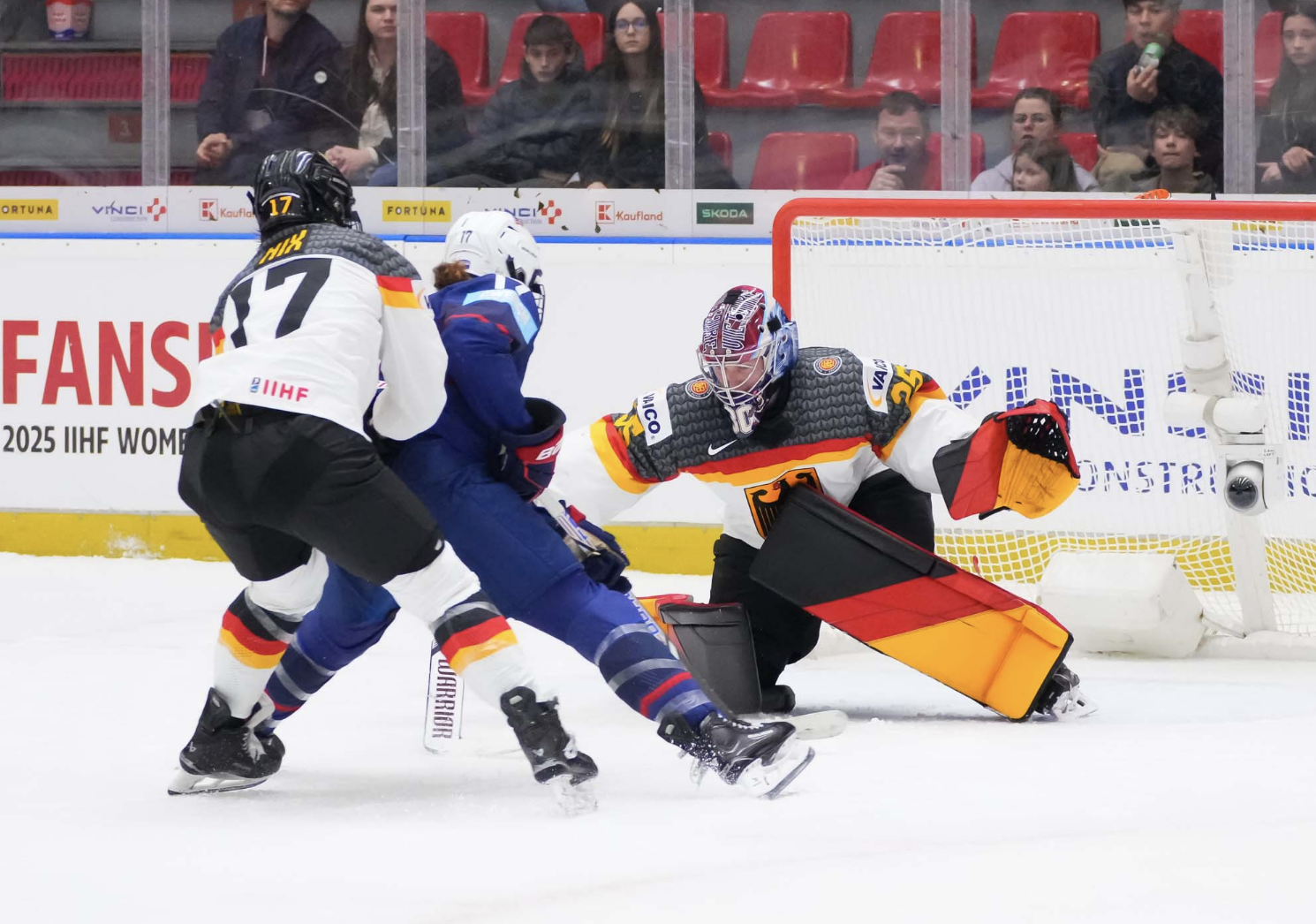 Abstreiter makes a poke check against USA's Britta Curl, who is being defended by Germany's Emily Nix. The Germans are wearing white uniforms, while Curl is in blue.