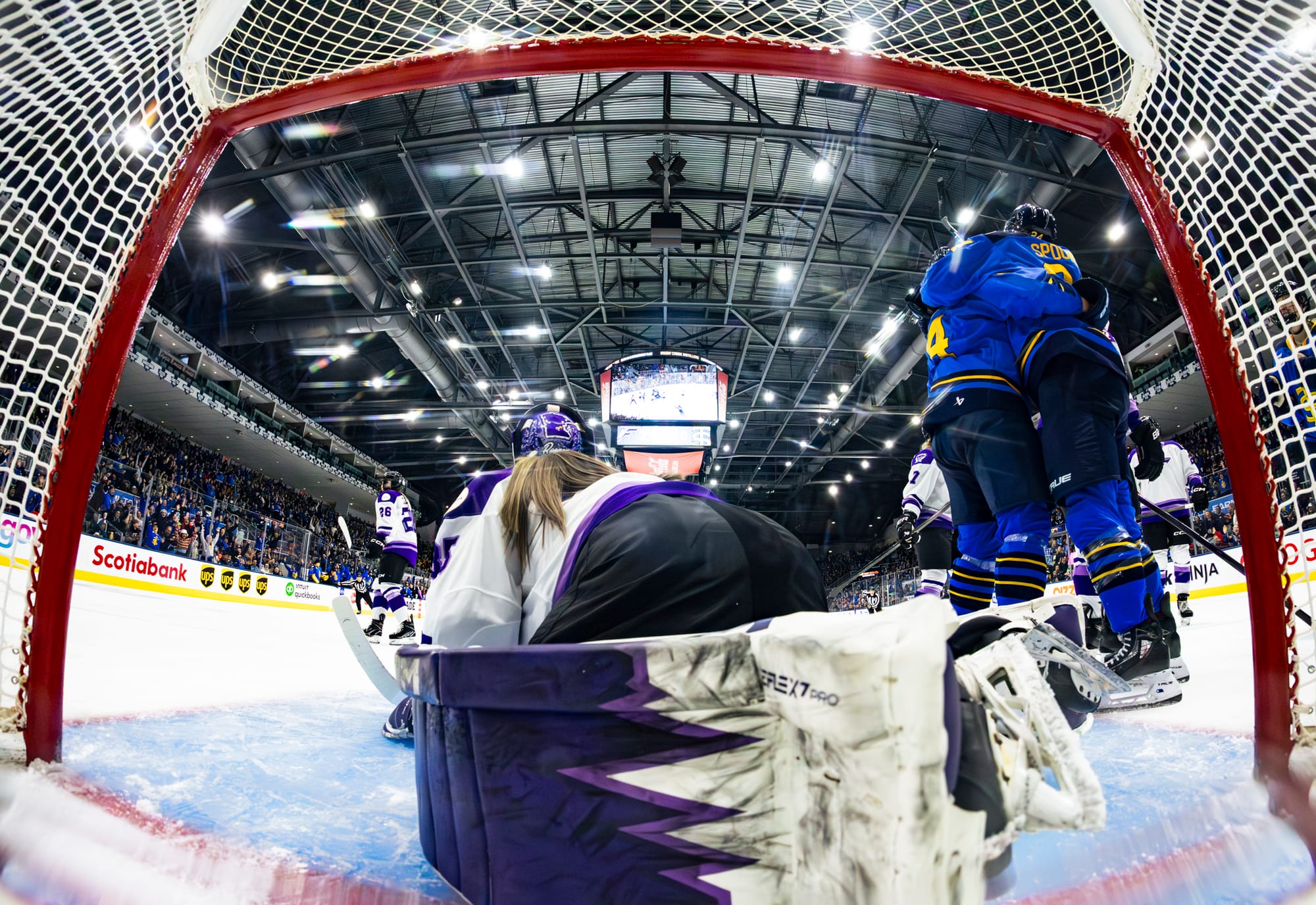 This photo is from the net camera. Miller and Spooner hug to Rooney's right, as Rooney is on her hands and knees after trying to make a save. Miller and Spooner are in blue home uniforms, while Rooney is in a white away one.