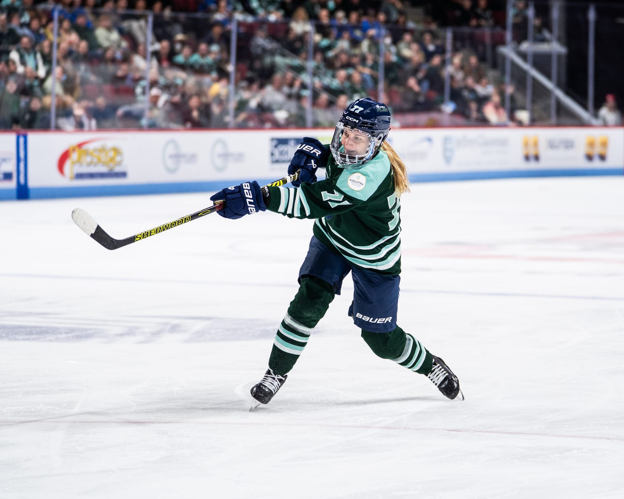 Tapani shifts her weight to her right foot as she follows through on her shot. She is wearing a green home uniform.