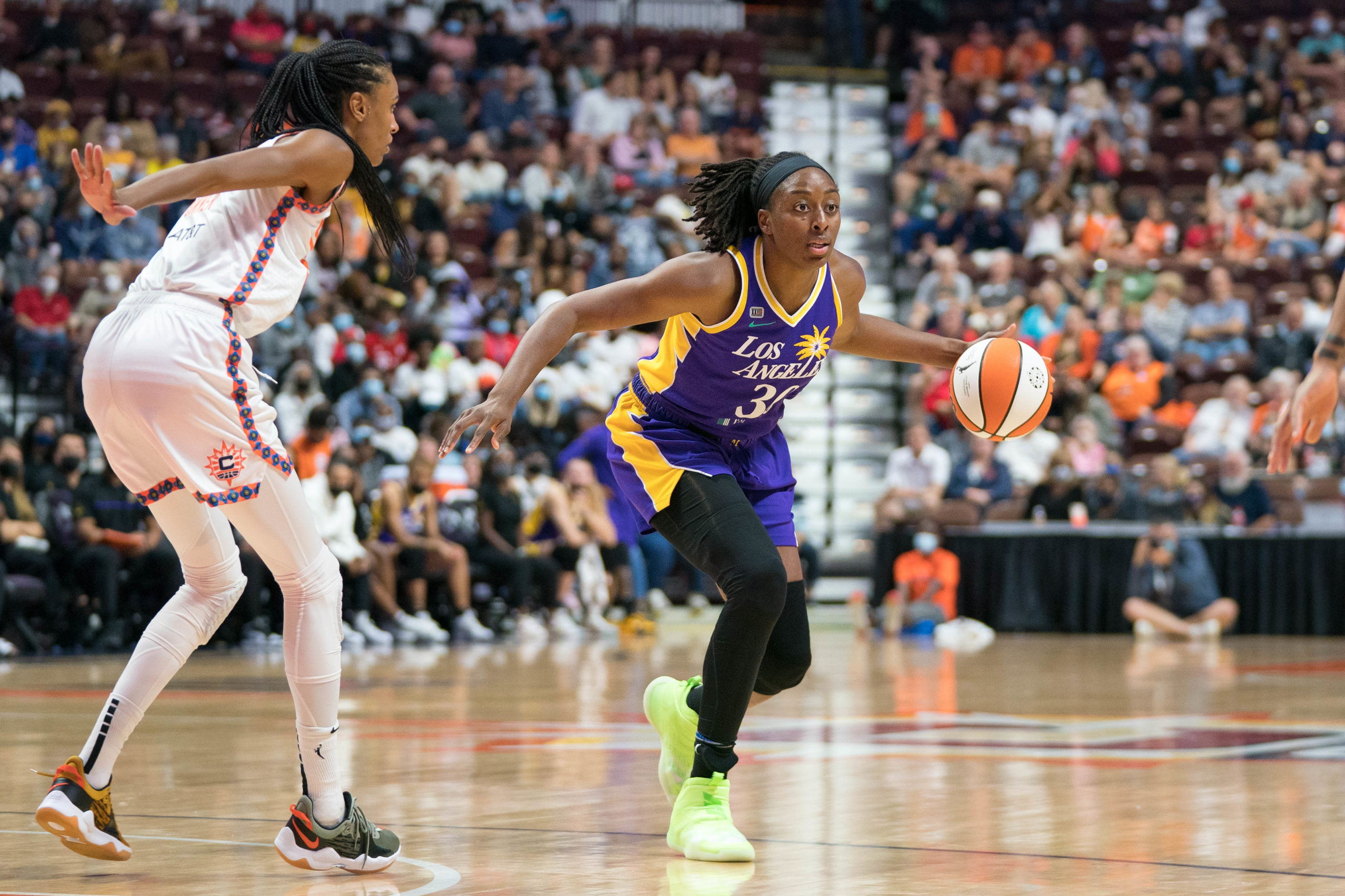 Los Angeles Sparks forward Nneka Ogwumike dribbles with her left hand as a Connecticut Sun defender stands about an arm's length away.
