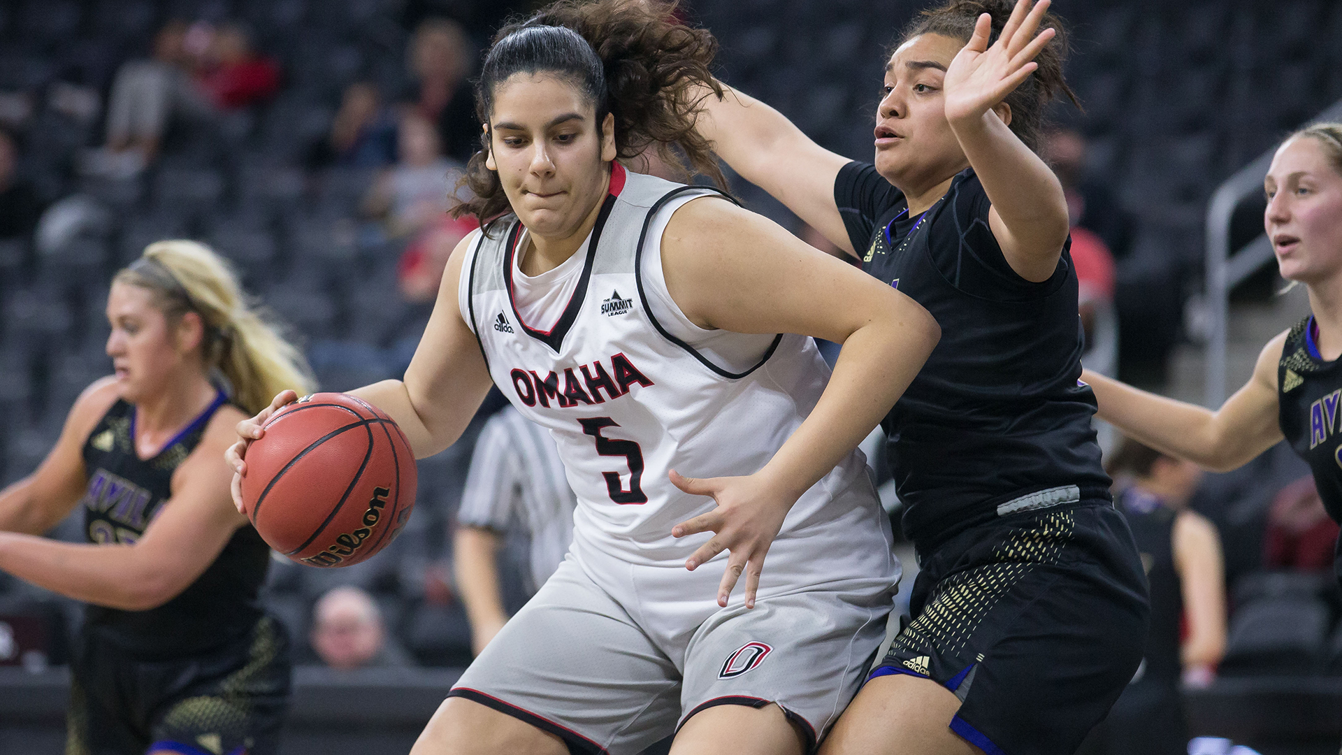 Elena Pilakouta posts-up, dribbling towards her left with the ball in her right hand, shielded from the defender.