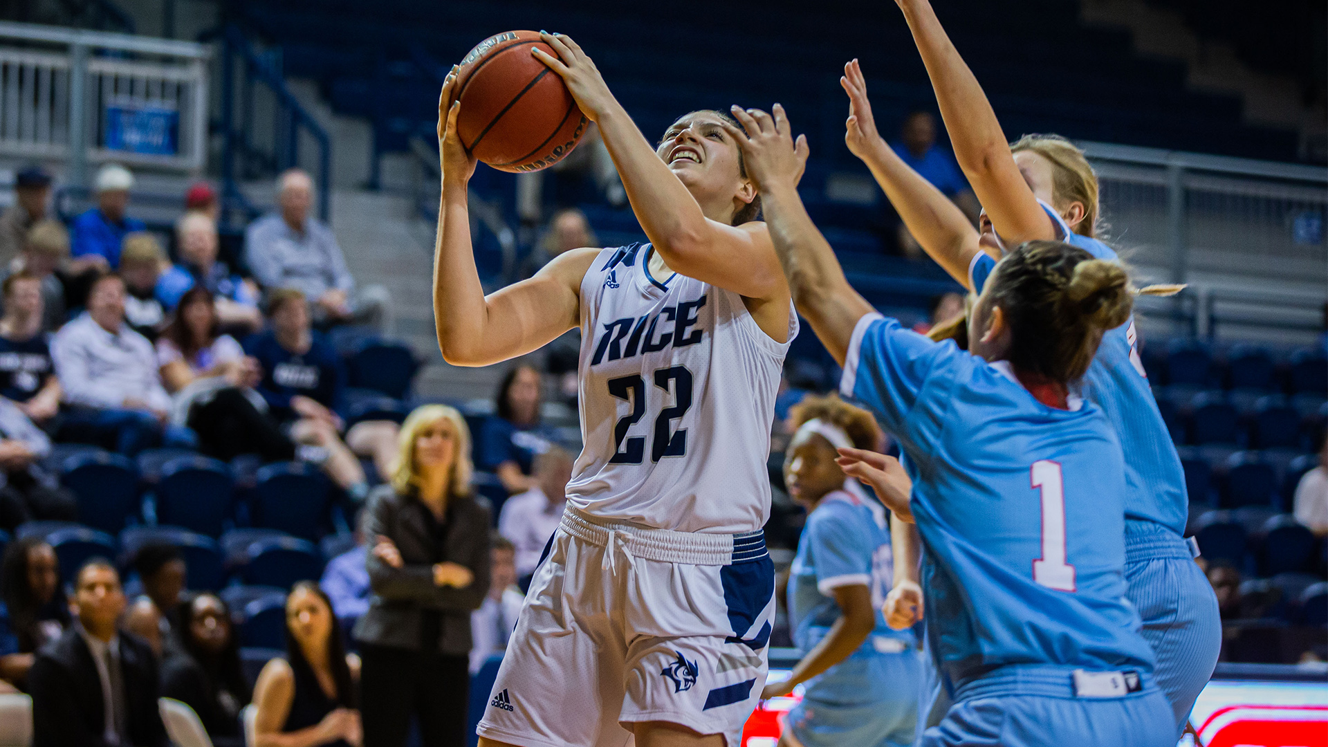 Ashlee Austin protects the ball with both hands as she goes up for a layup in front of two defenders.