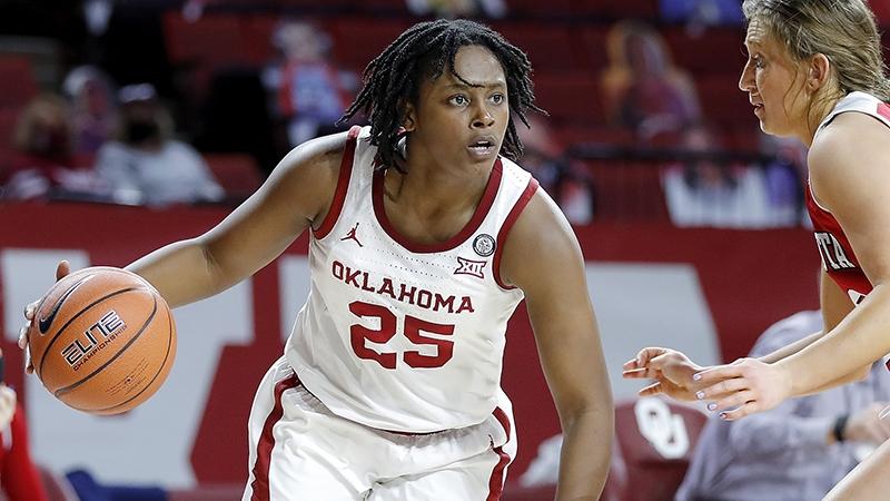 Madi Williams attacks while dribbling with her right hand, shielding it from a defender.