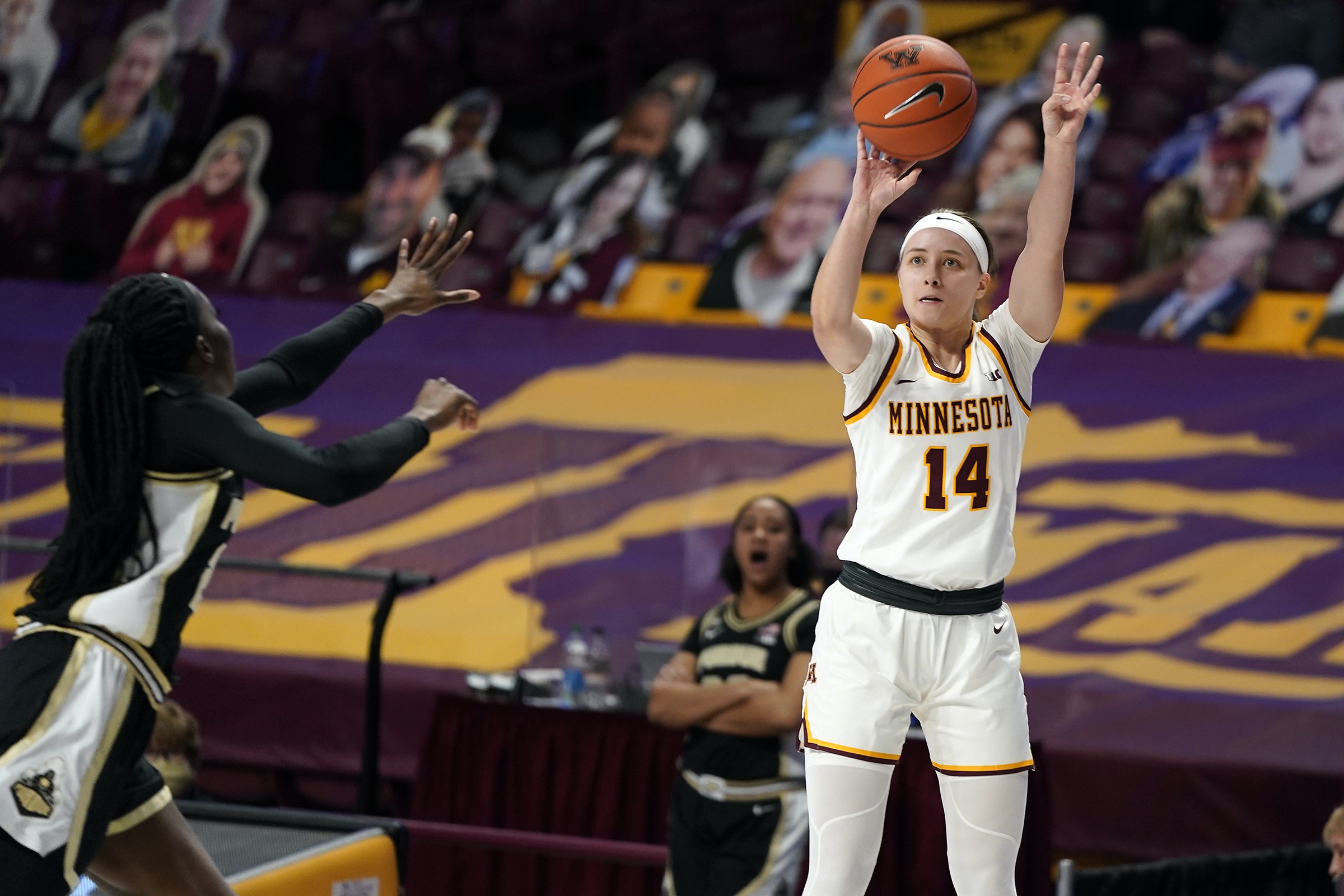 Sara Scalia is at the mid-air peak of her shooting motion, with the ball resting on just her shooting fingertips as a defender attempts to close-out from a considerable distance.