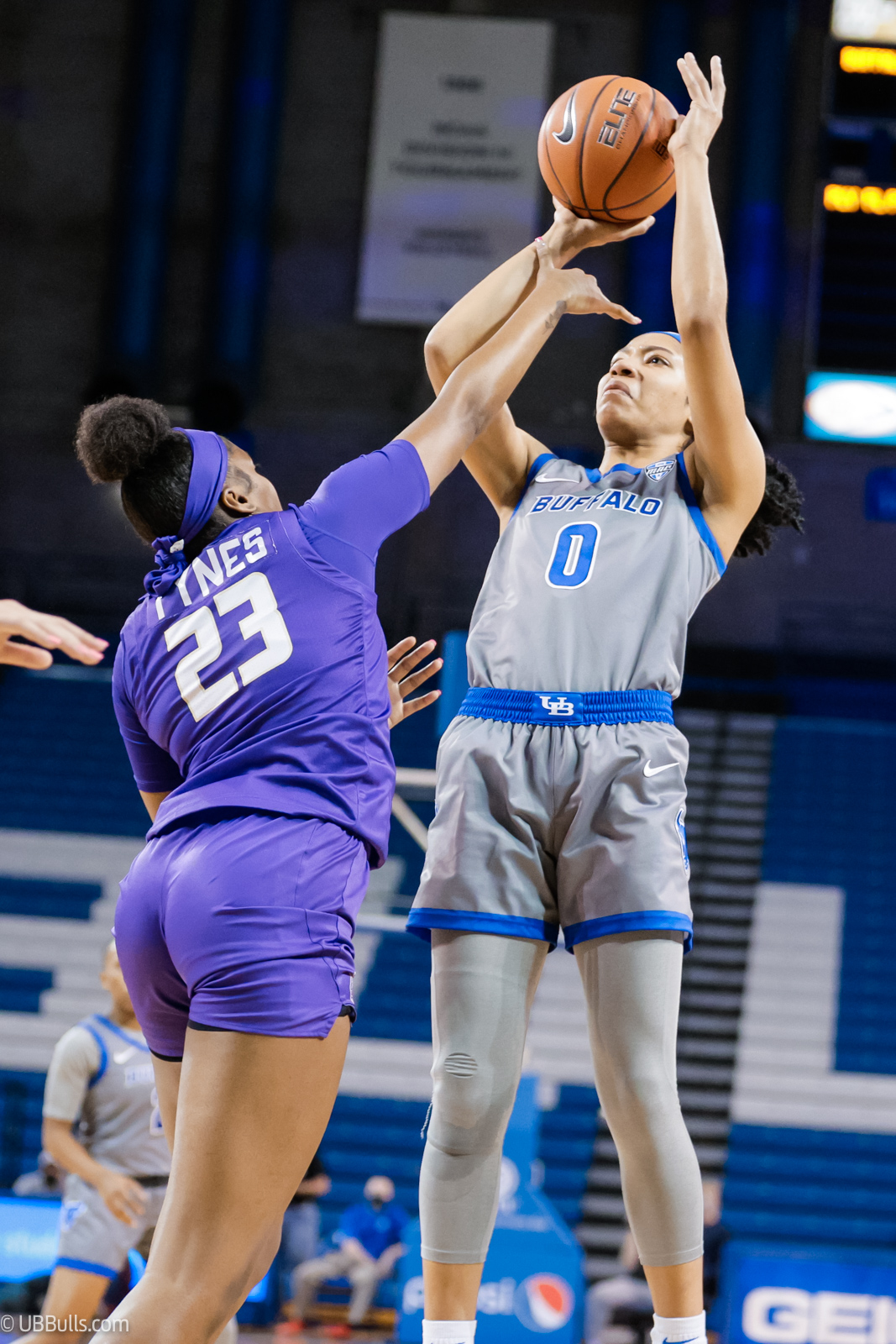 Summer Hemphill readies to release the ball on a jump shot with a defenders' hand between Hemphill's arms, square in her face.