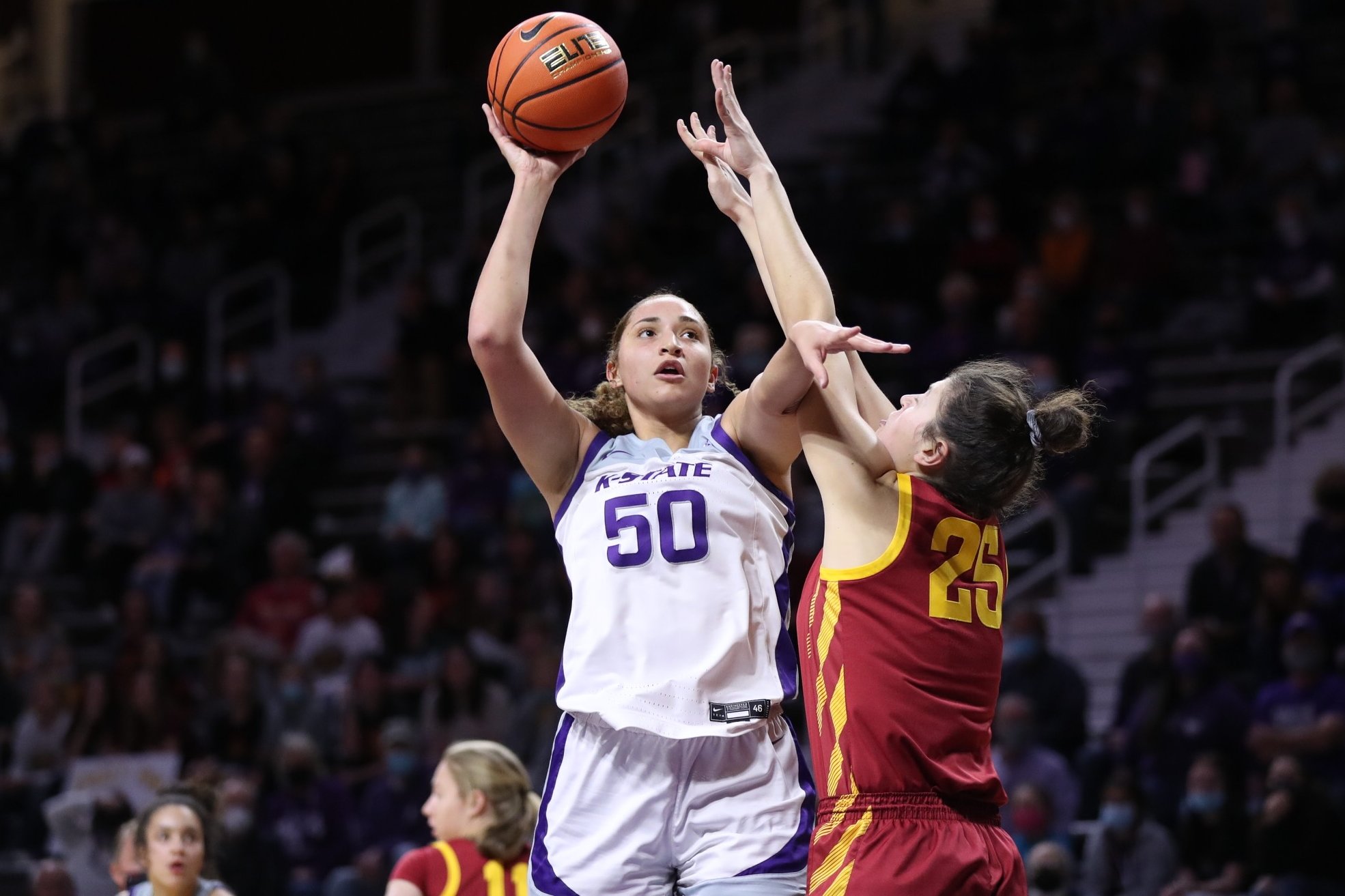 Ayoka Lee shields off a defender with her left arm while putting the ball up for a layup with her right arm