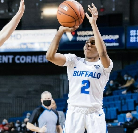 Dyaisha Fair begins to release the ball as a defender's hand closes towards her face
