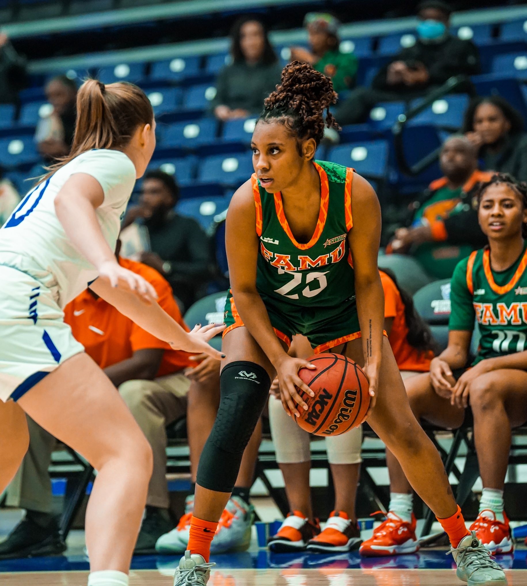 Dylan Horton holds the ball in a low triple-threat position while a defender faces her up near the break.