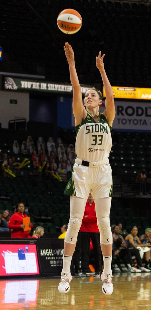 Katie Lou Samuelson, midair, watches the ball with arms outstretched just after releasing a jumper
