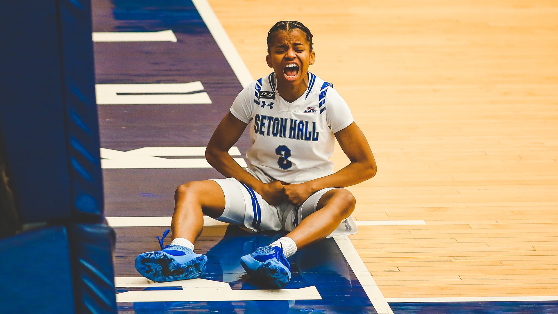 Lauren Park-Lane sits on the baseline facing away from the basket, flexing downwards and screaming in celebration