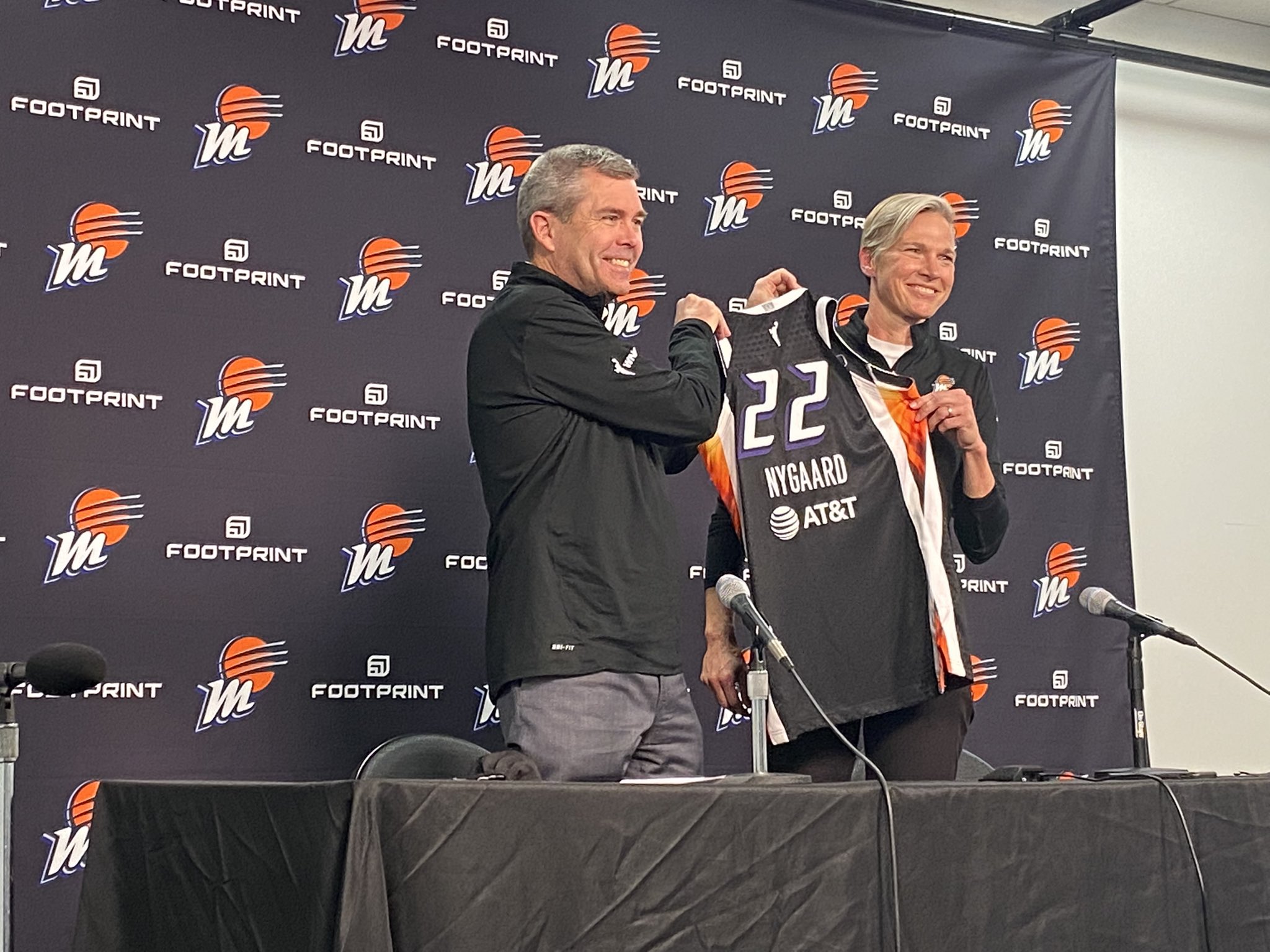 Vanessa Nygaard and Jim Pitman holding up a Mercury jersey at her introductory press conference
