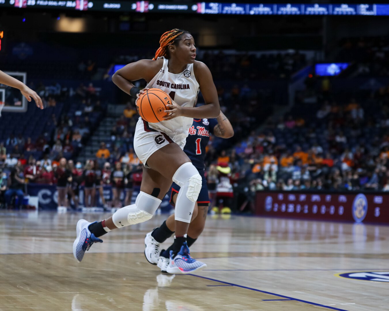 Aliyah Boston carries the ball as she strides past a defender and towards the rim