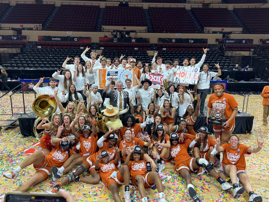 Members of the Texas Longhorns team and pep band gather at halfcourt and pose in celebration
