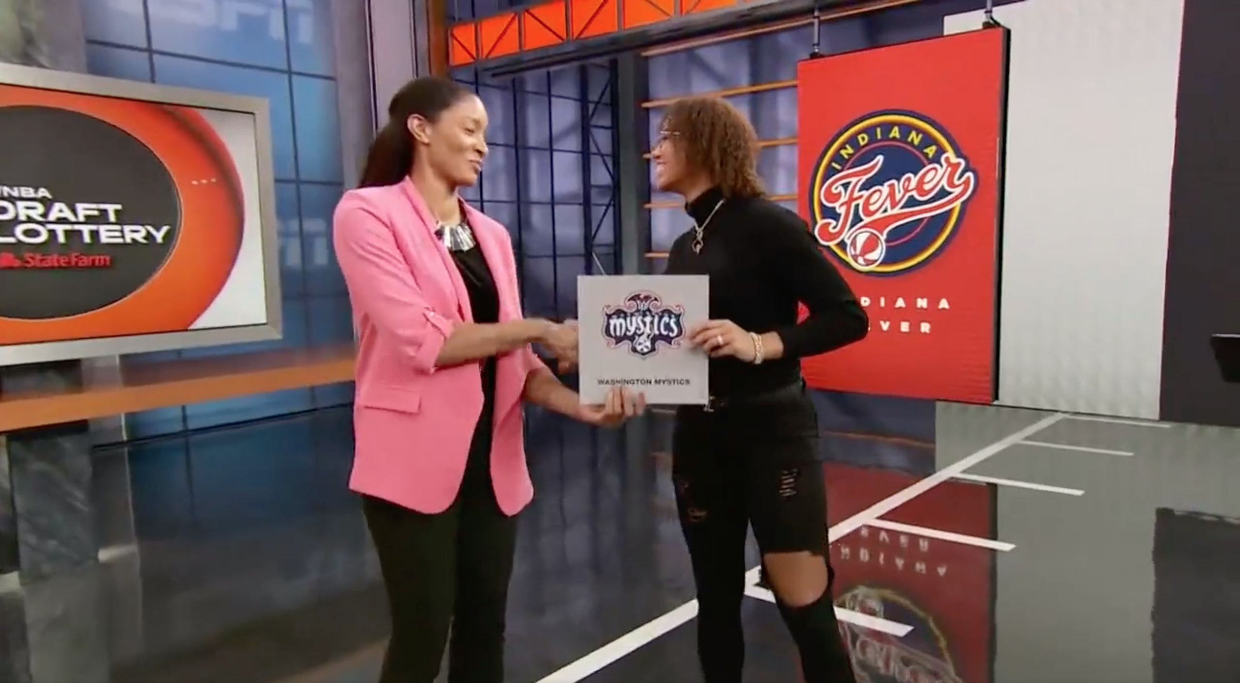 Washington Mystics point guard Natasha Cloud shakes hands with Bethany Donaphin, head of league operations for the WNBA, after the Mystics secured the No. 1 overall pick in the 2022 WNBA Draft.