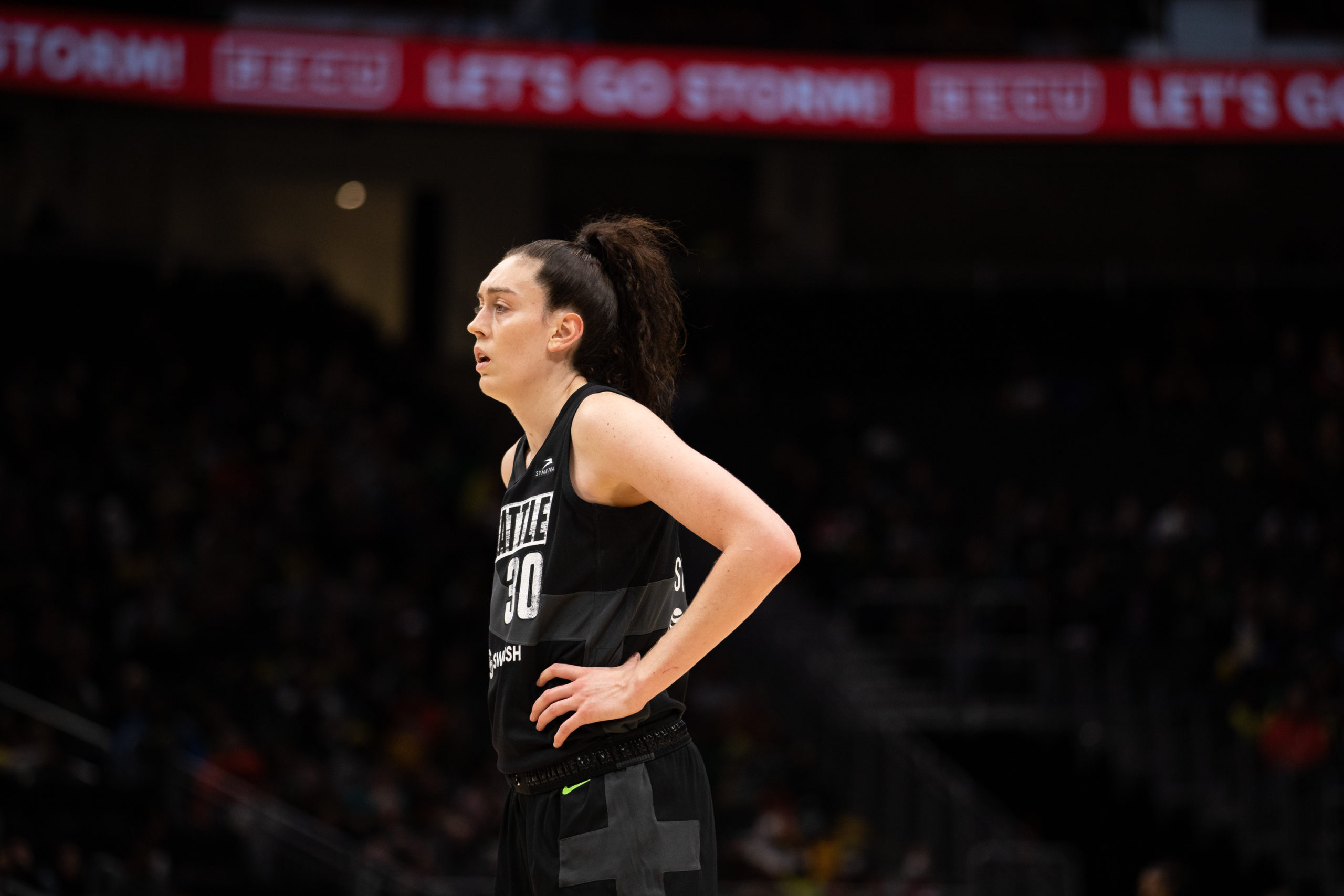 Seattle Storm big wing Breanna Stewart stands with her hands on her hips, photographed from a side angle.