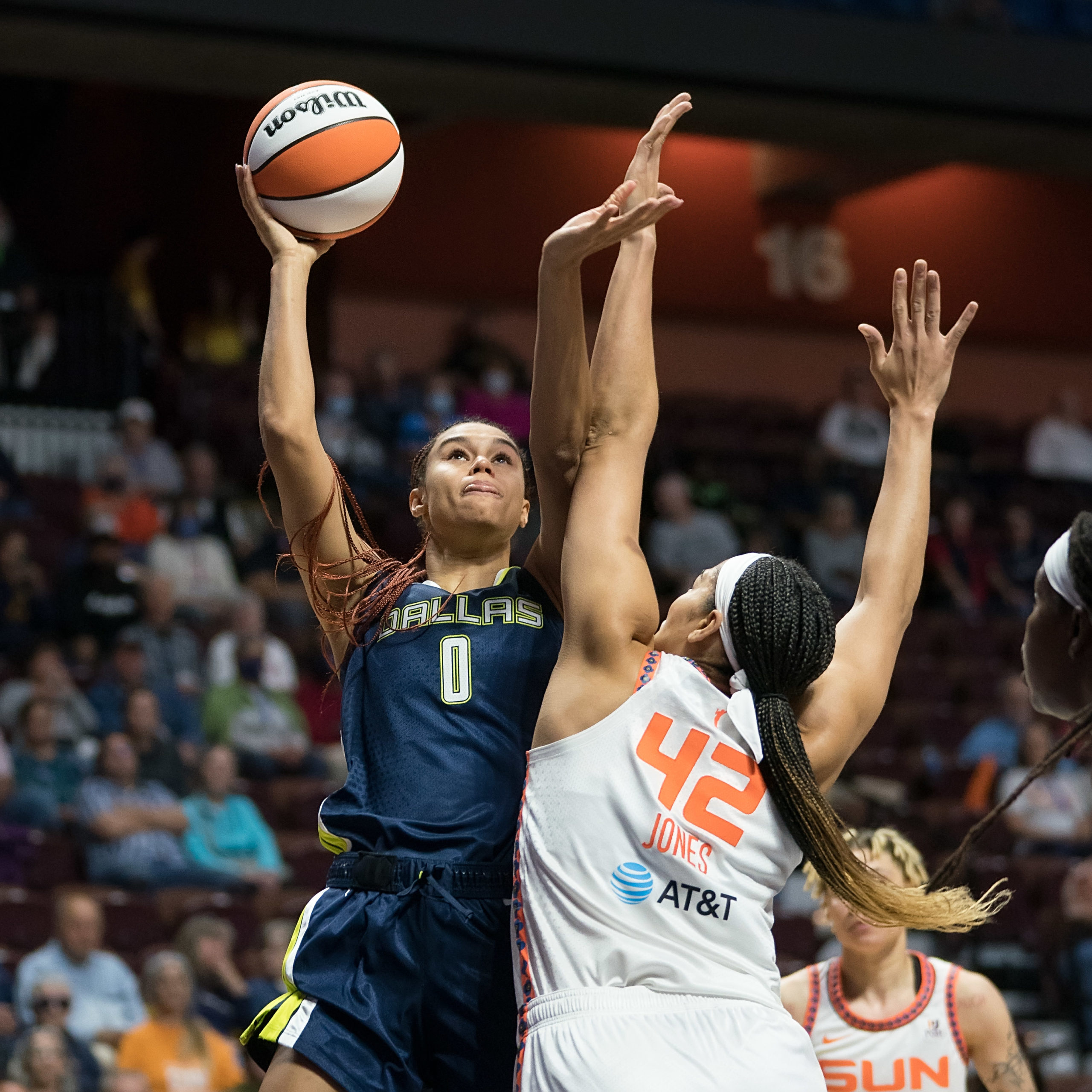 Dallas Wings big wing Satou Sabally looks towards the rim and releases the ball with one hand, while using her other arm to shield from a contest from Connecticut Sun center Brionna Jones