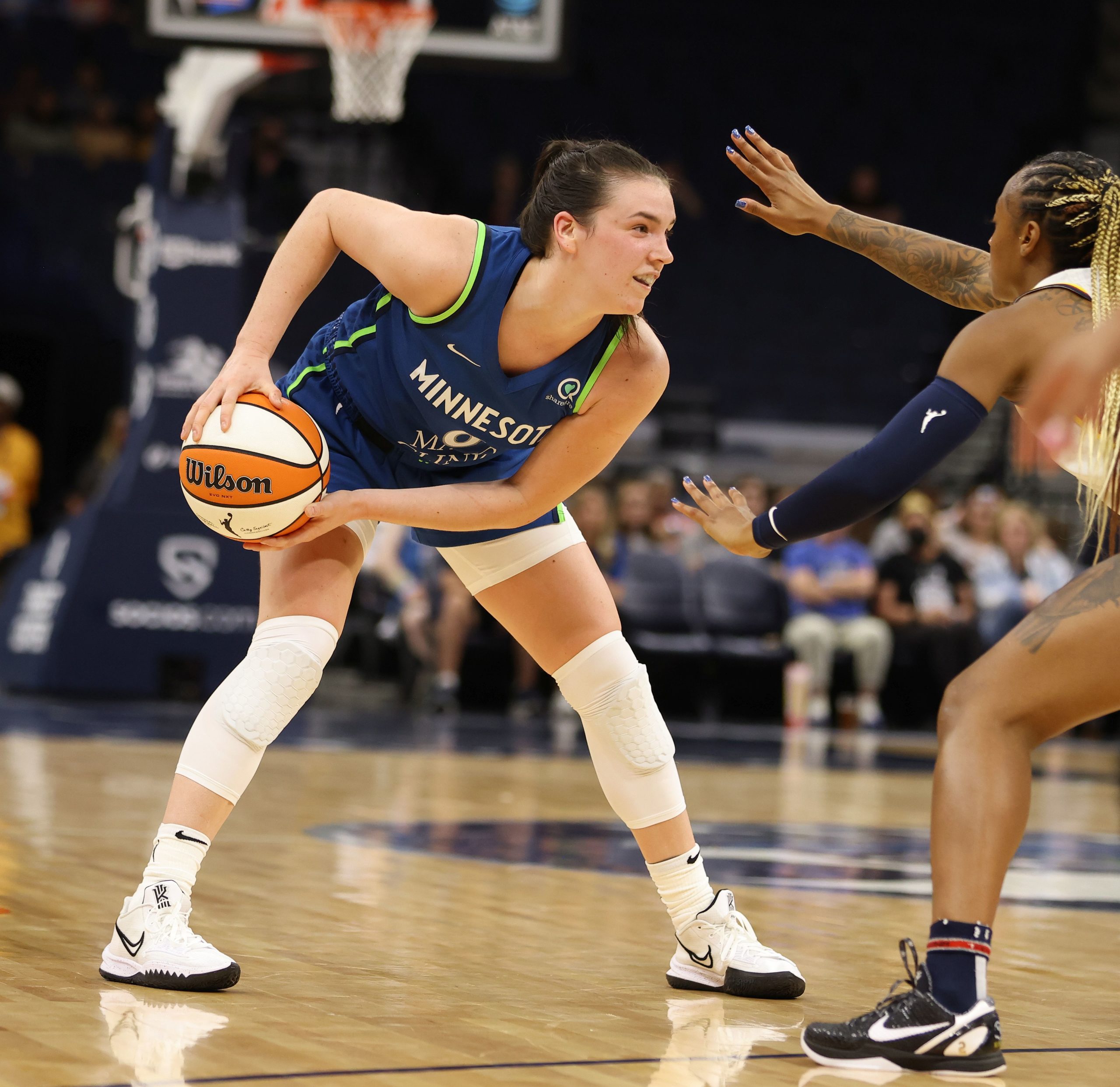 Minnesota Lynx off-ball guard Bridget Carleton stands near the key in a triple-threat stance while looking across the court, as an Indiana Fever defender holds her arms out towards Carleton to obscure her sightlines