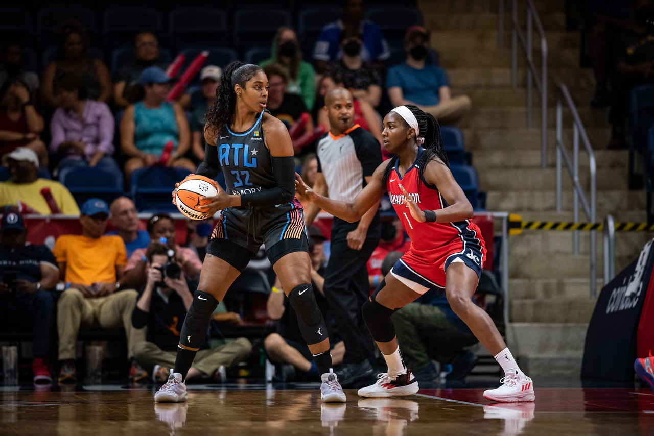 Atlanta Dream big Cheyenne Parker holds the ball in the post just outside the paint and surveys the court while being guarded by Washington Mystics center Elizabeth Williams