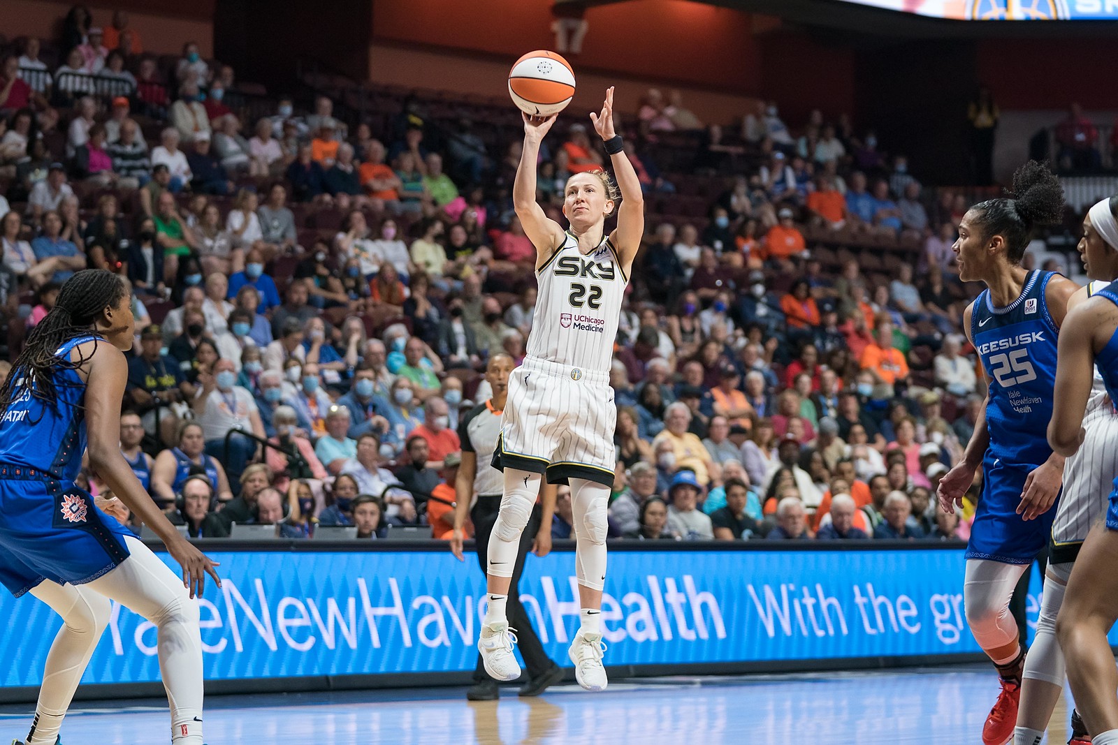 Chicago Sky point guard Courtney Vandersloot, mid-air, releases a jump shot off her fingertips, as a Connecticut Sun defender watches on from either side of her