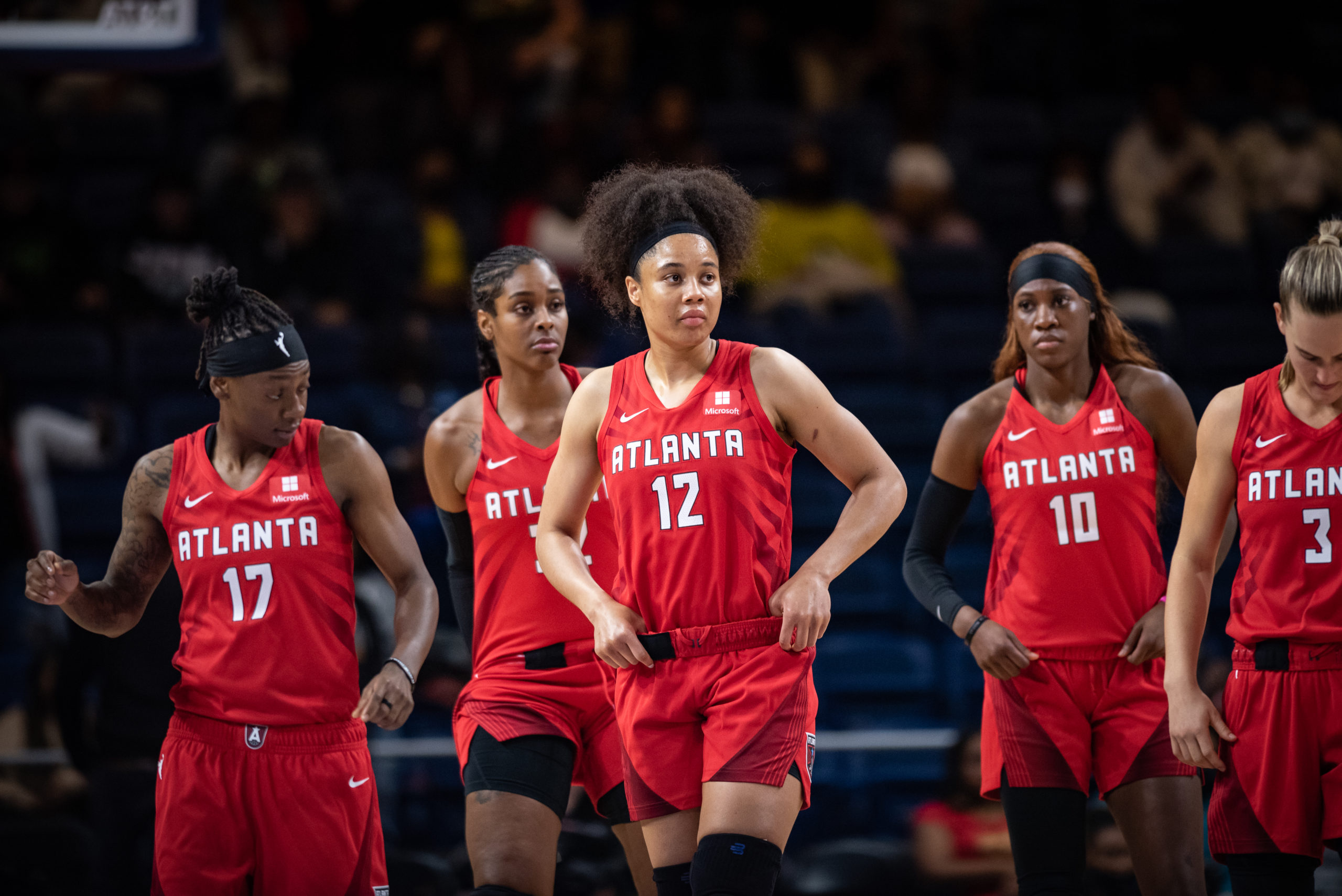 Members of the Atlanta Dream stand on the court. They are, from left to right: Erica Wheeler, Cheyenne Parker, Rhyne Howard, and Kristy Wallace, with Nia Coffey in front of them