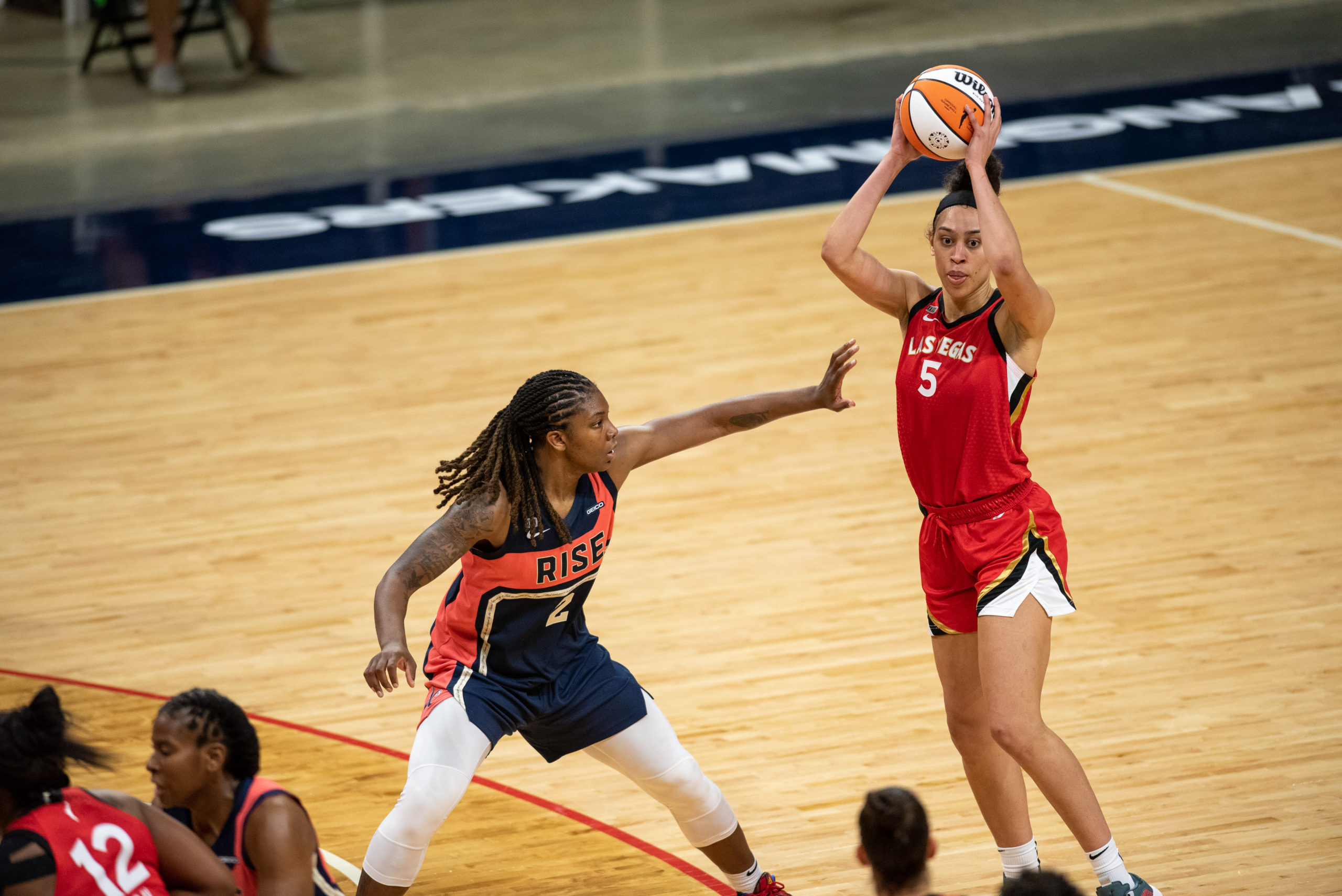 Dearica Hamby holds the ball above her head at the top of the key with a defender on her.