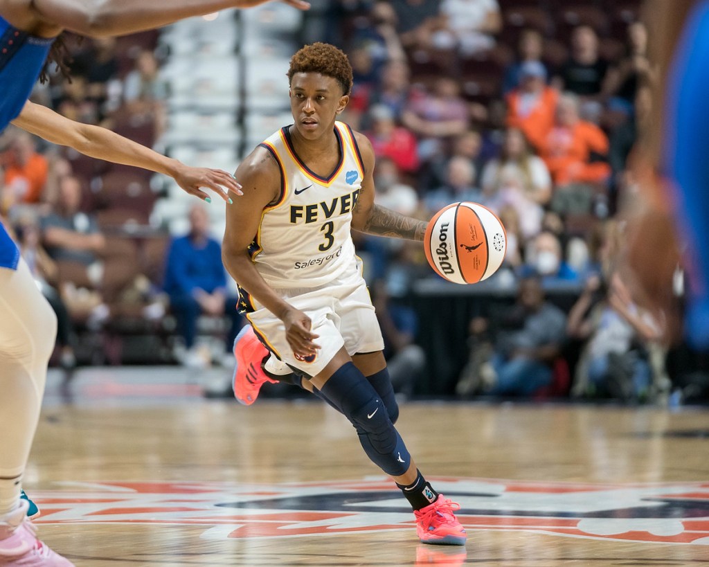 Indiana Fever point guard Danielle Robinson dribbles up the court while a Connecticut Sun defender holds an arm out to stay in front of her