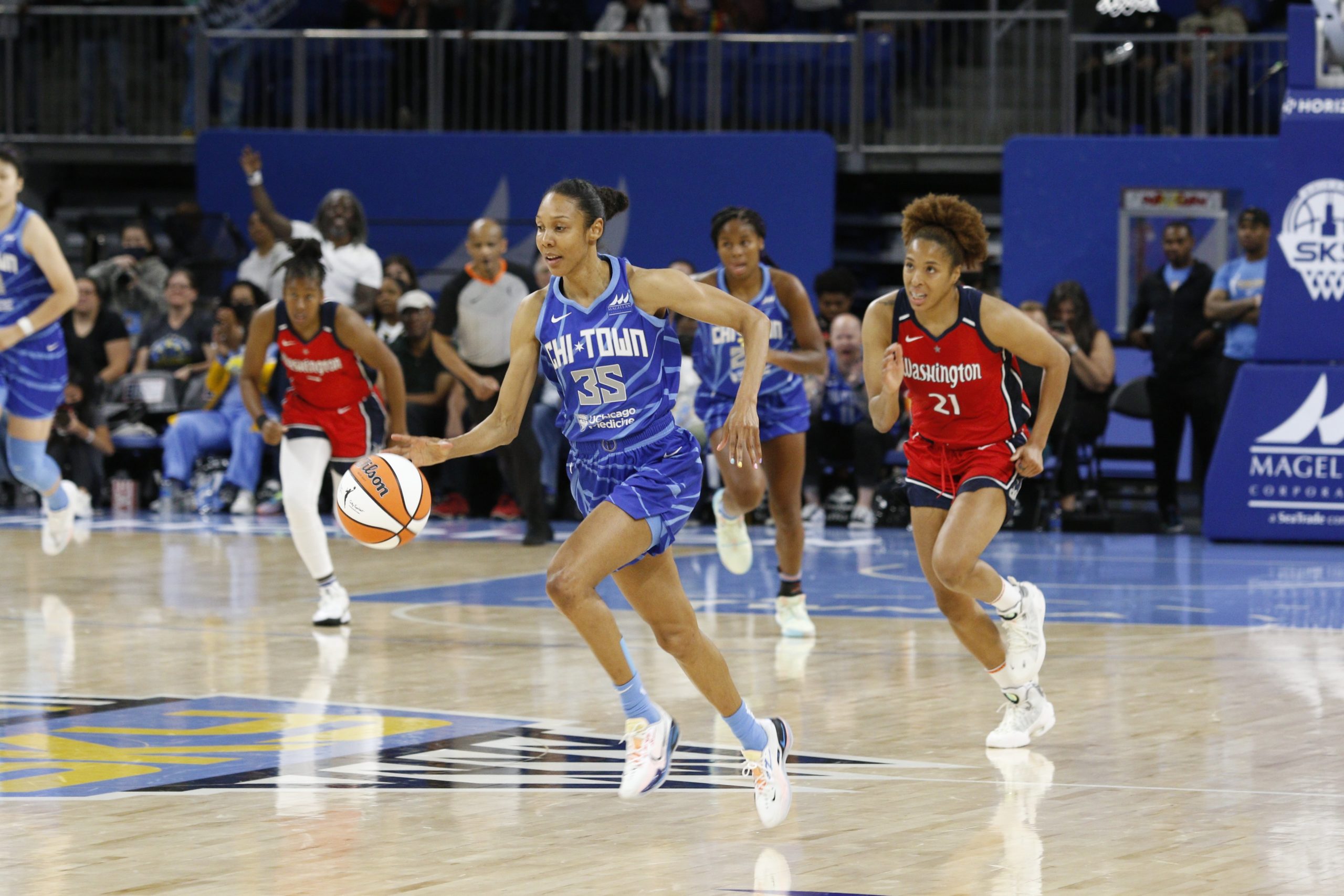 Sky small forward Rebekah Gardner (35) brings the ball up the court with Mystics power forward Tianna Hawkins (21) on her heels. Other Sky and Mystics players follow them from behind.