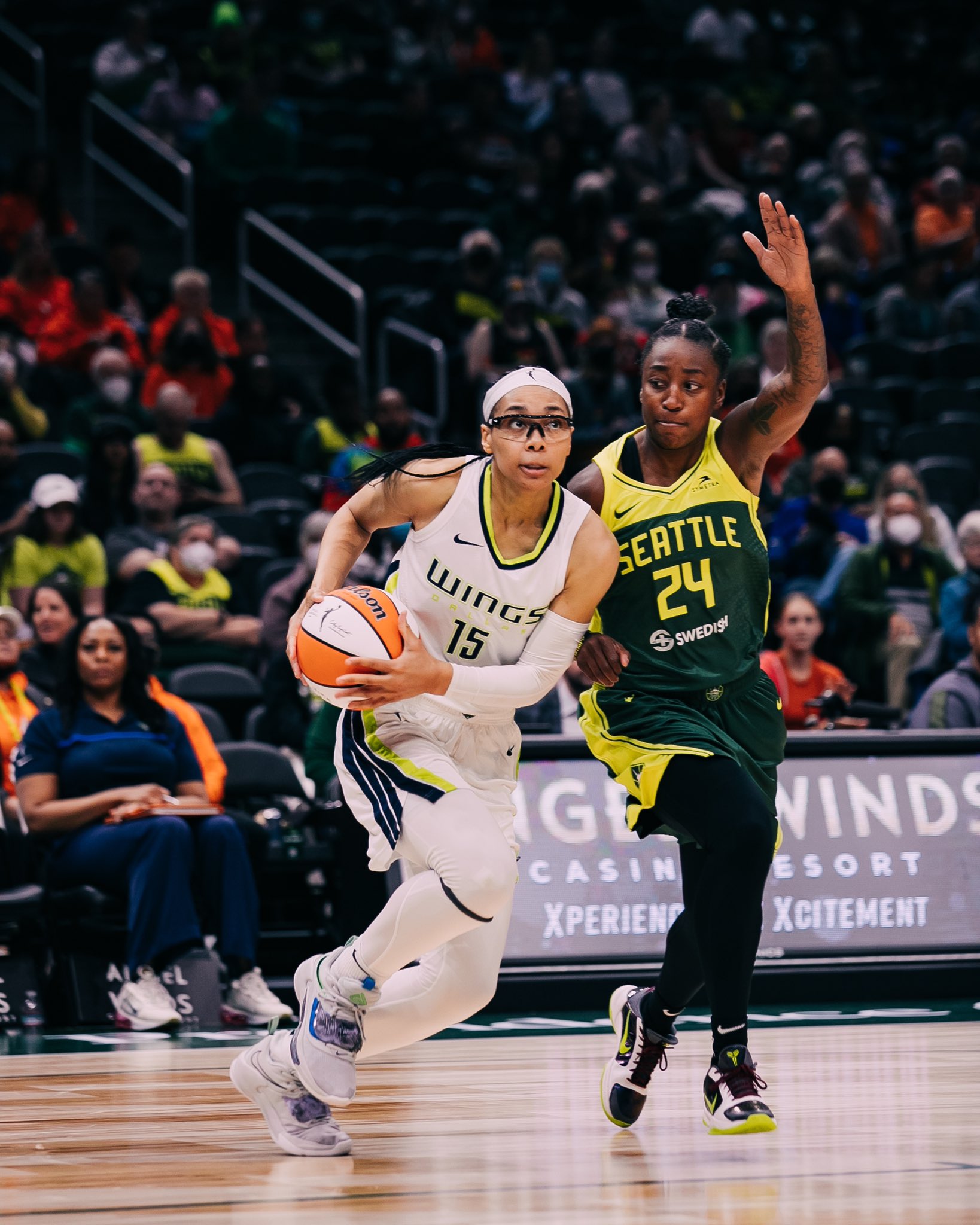 Dallas Wings shooting guard Allisha Gray gathers the ball as she drives to the basket with Seattle Storm guard Jewell Loyd right behind her, with one hand raised.
