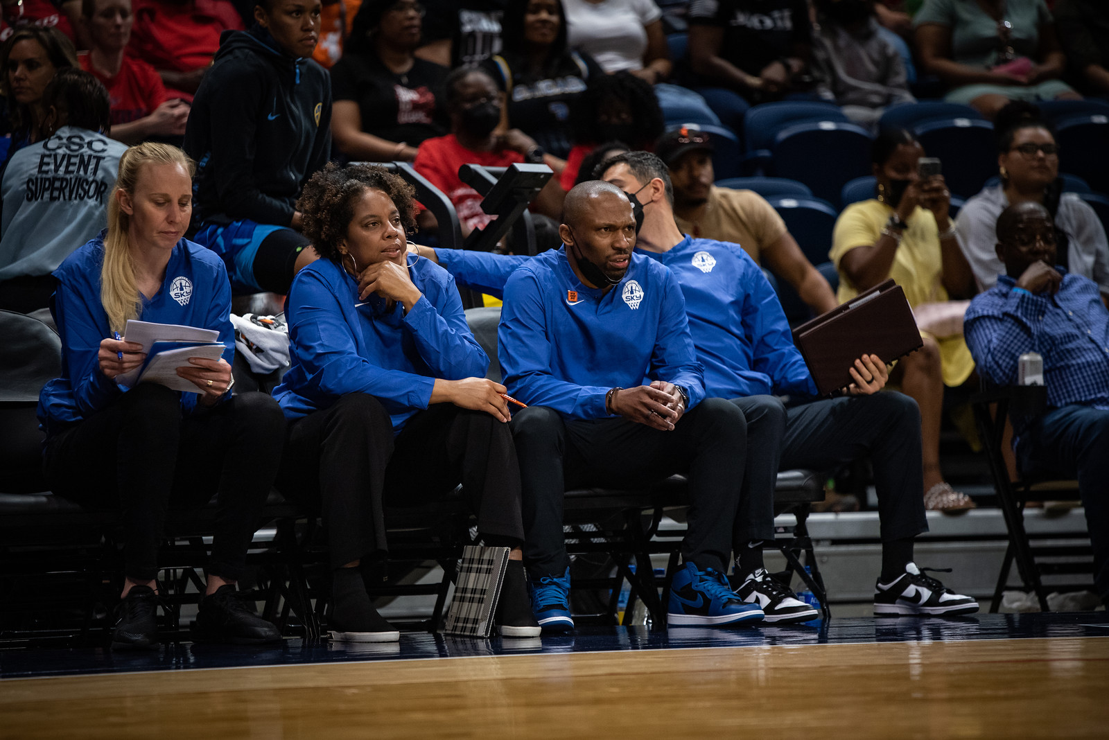 Chicago Sky head coach James Wade and his assistant coaches sit on the bench and look out towards the court, with Wade looking disgusted by what he's seeing