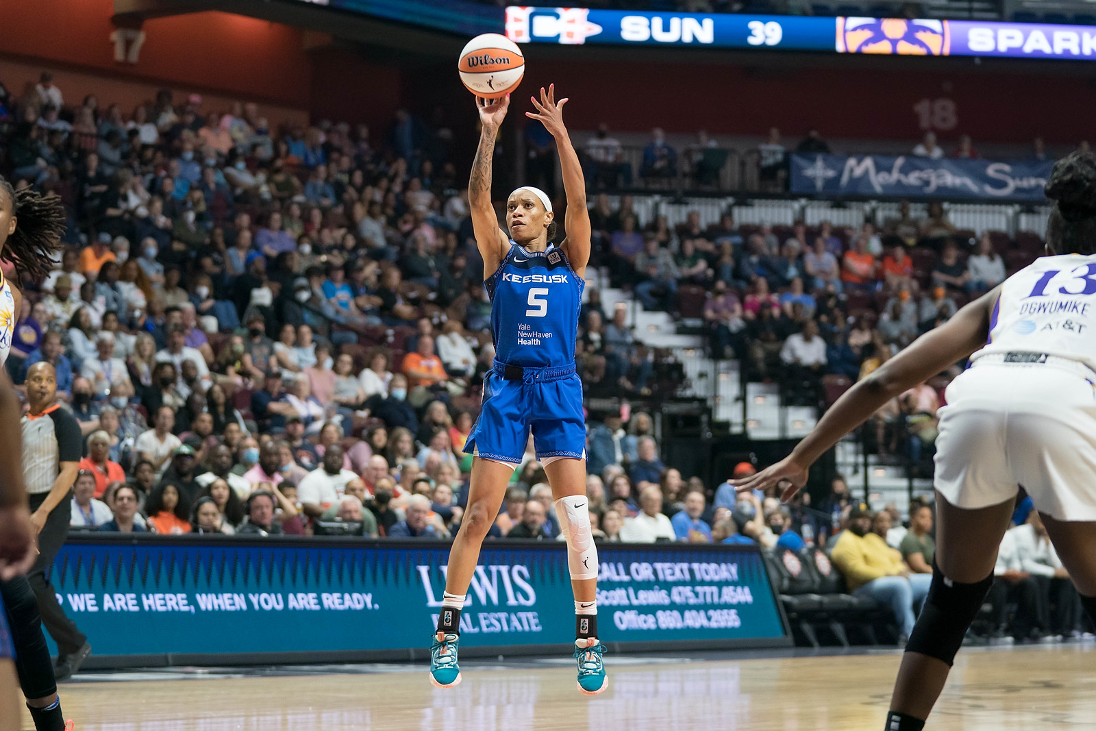 Connecticut Sun point guard Jasmine Thomas, mid-air, releases the ball off her fingertips for a jump shot