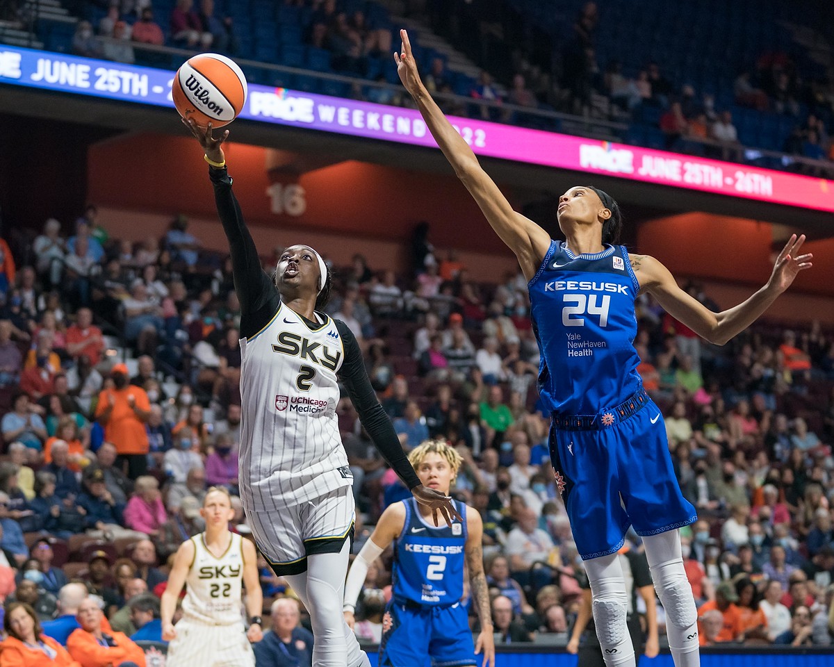 Chicago Sky wing Kahleah Copper extends one arm with the ball towards the rim as she shoots a layup, while Connecticut Sun big wing DeWanna Bonner lunges toward her with an outstretched arm in an attempt to block the shot
