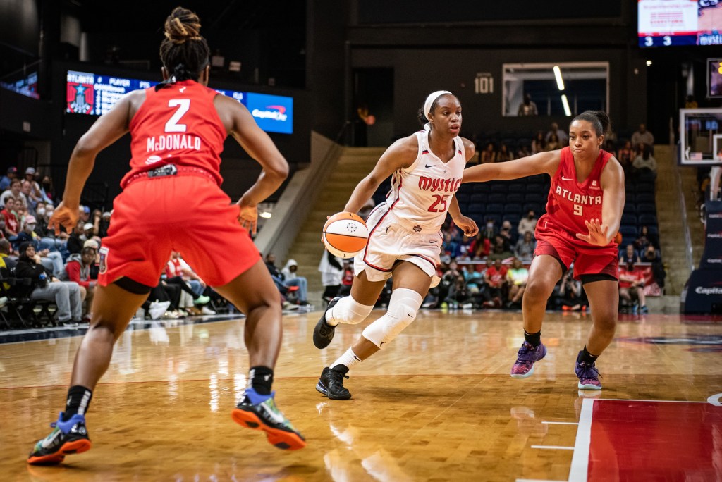 Washington Mystics combo forward Kennedy Burke dribbles past a lunging Atlanta combo forward Megan Walker, while Dream point guard Aari McDoland watches on