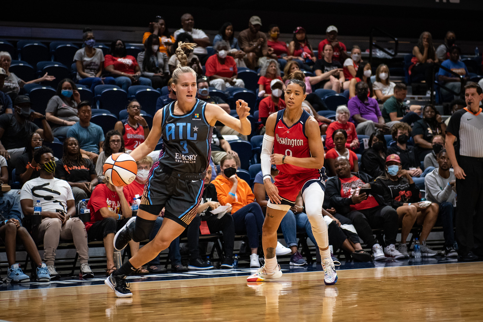 Atlanta Dream off-ball guard Kristy Wallace dribbles while driving baseline from the corner as Washington Mystics point guard Natasha Cloud stands at the arc watching Wallace go by.