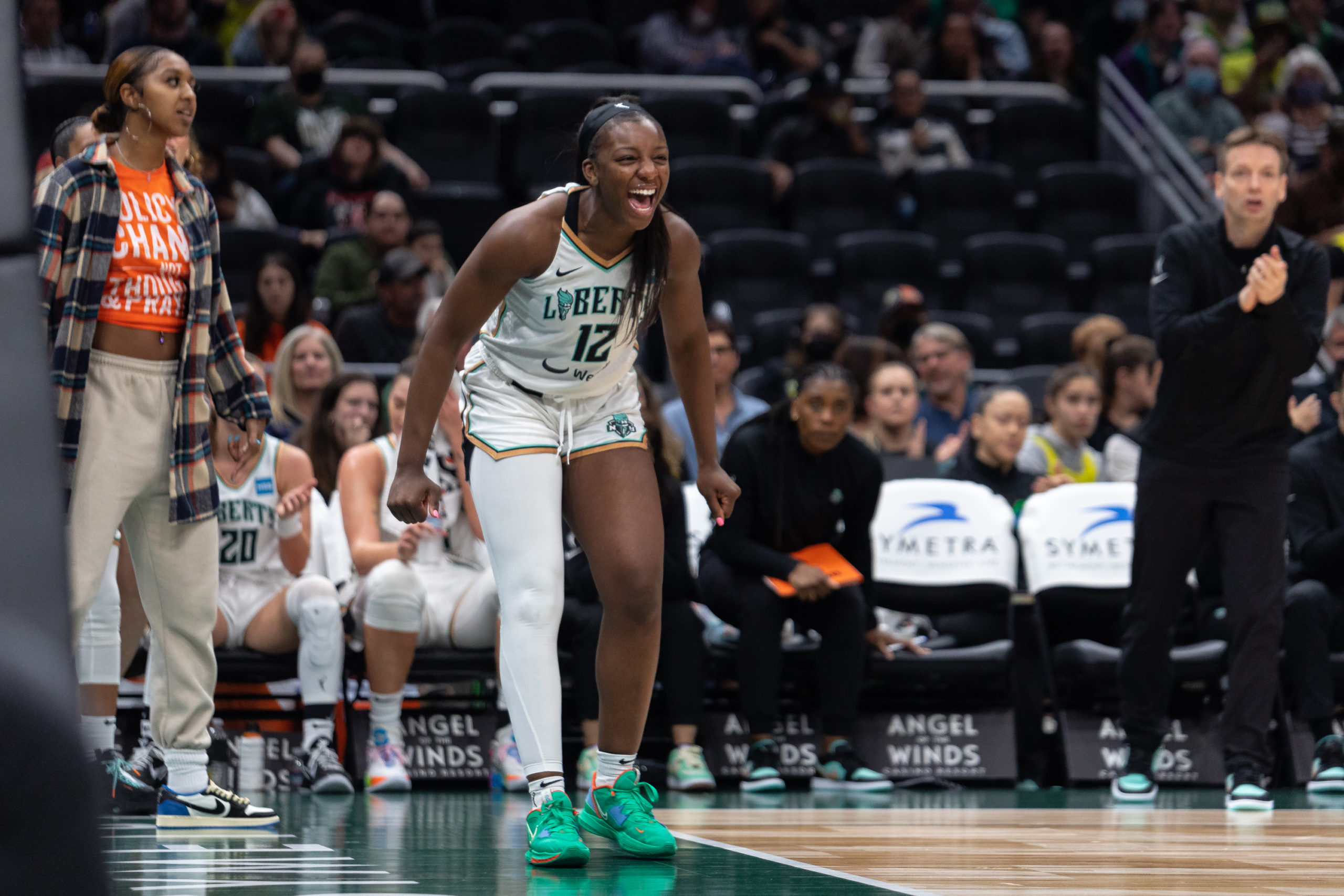 New York Liberty combo forward Michaela Onyenwere leans forward and screams in celebration in front of the Liberty bench.