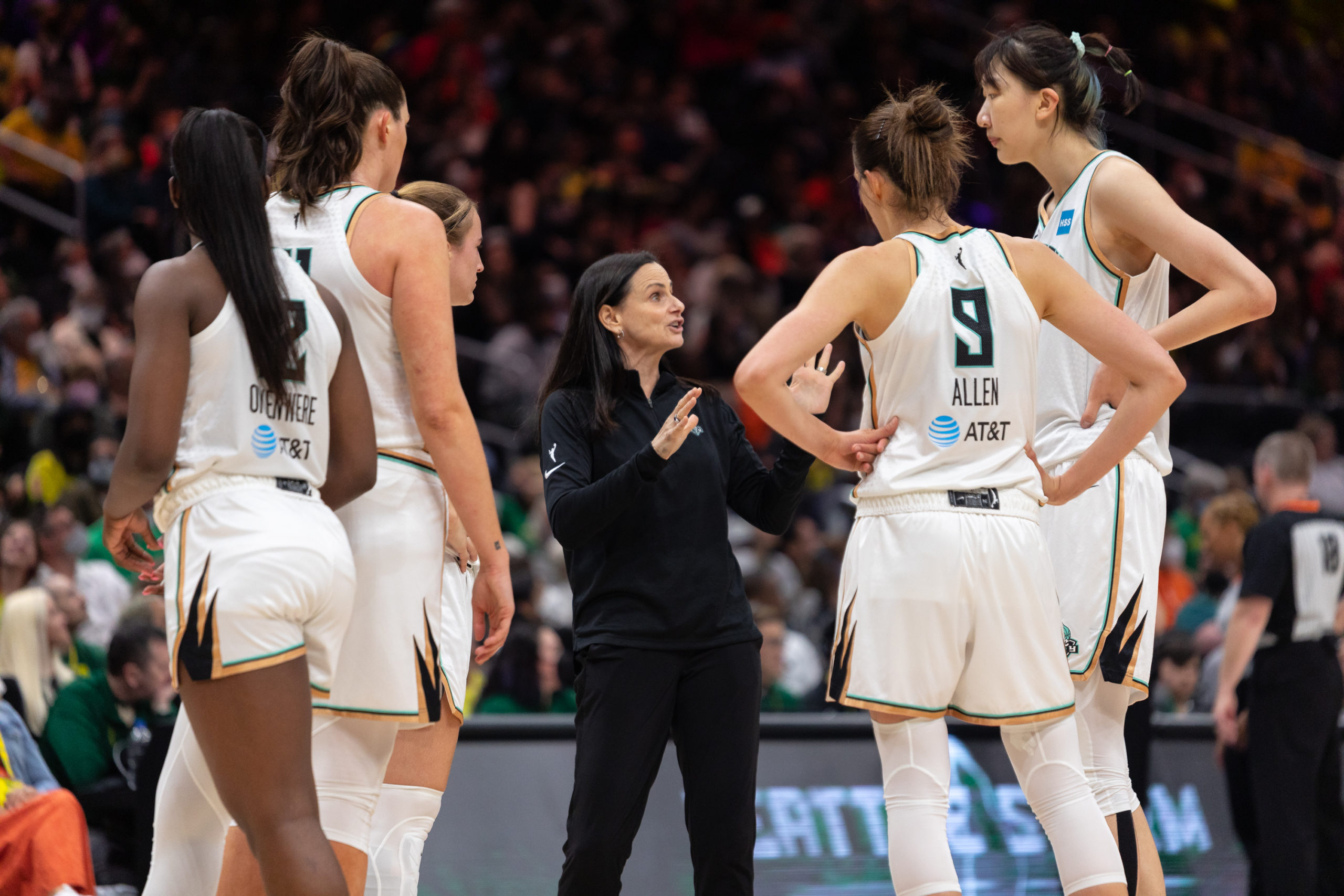 Members of the New York Liberty gather on the court around head coach Sandy Brondello, including Han Xu, Rebecca Allen, Michaela Onyenwere, Stefanie Dolson, and Sabrina Ionescu