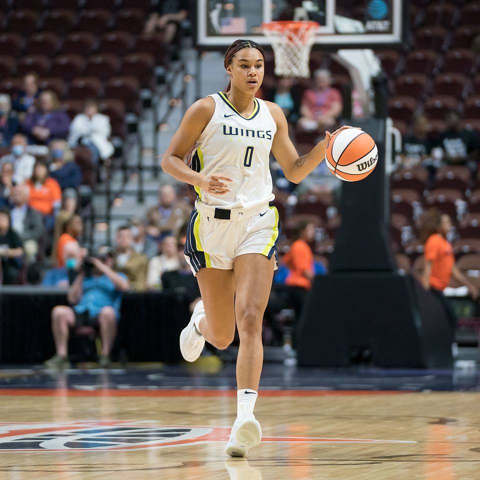Dallas Wings big wing Satou Sabally dribbles up the court past the halfcourt logo, while moving and looking towards the slot