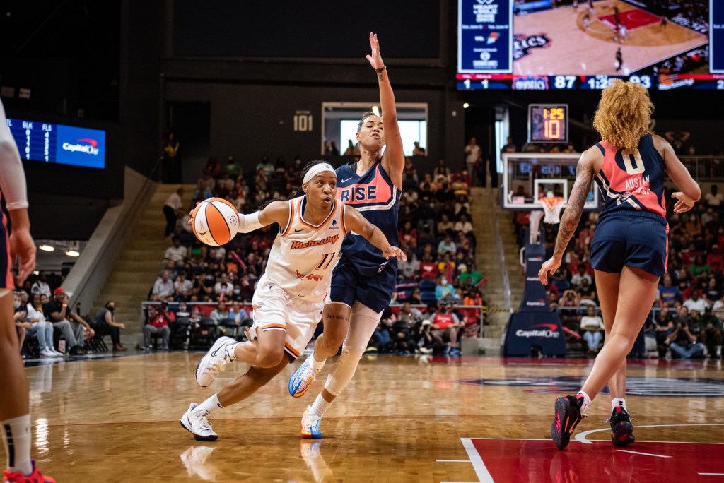 Phoenix Mercury point guard Shey Peddy has the ball out to her side as she drives from the slot to the hoop, while keeping Washington Mystics point guard Natasha Cloud on her hip, who has an arm up to contest a possible