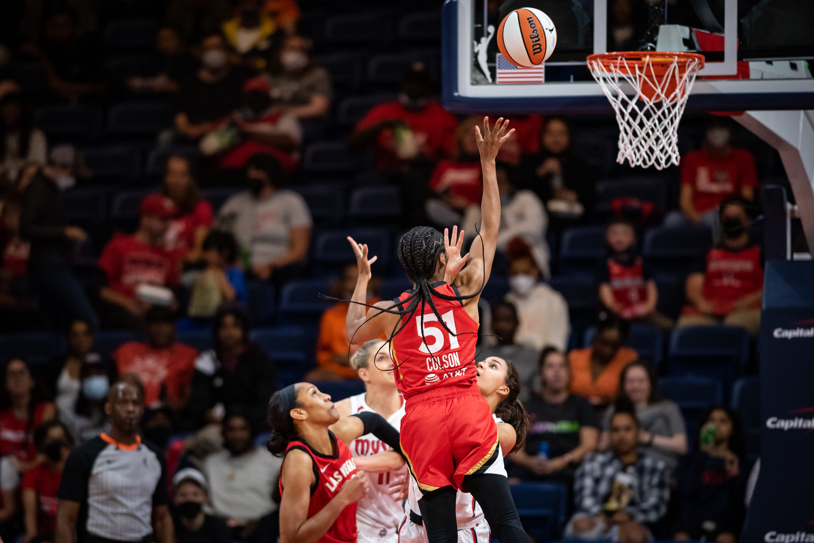 Las Vegas Aces point guard Sydney Colson releases a floater in mid-air right in front of the rim while a teammate and Washington Mystics defenders battle under the rim
