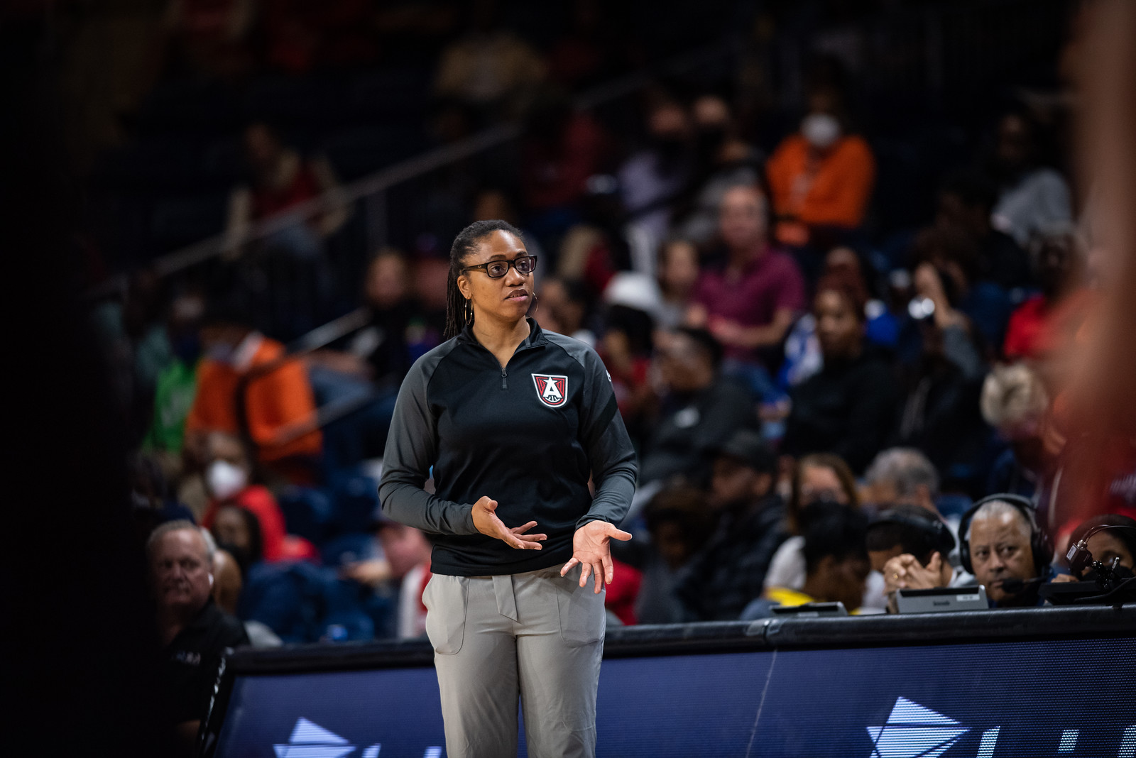 Atlanta Dream head coach Tanisha Wright stands at mid-court looking towards the baseline, with her hands down and out in a state of mild confusion