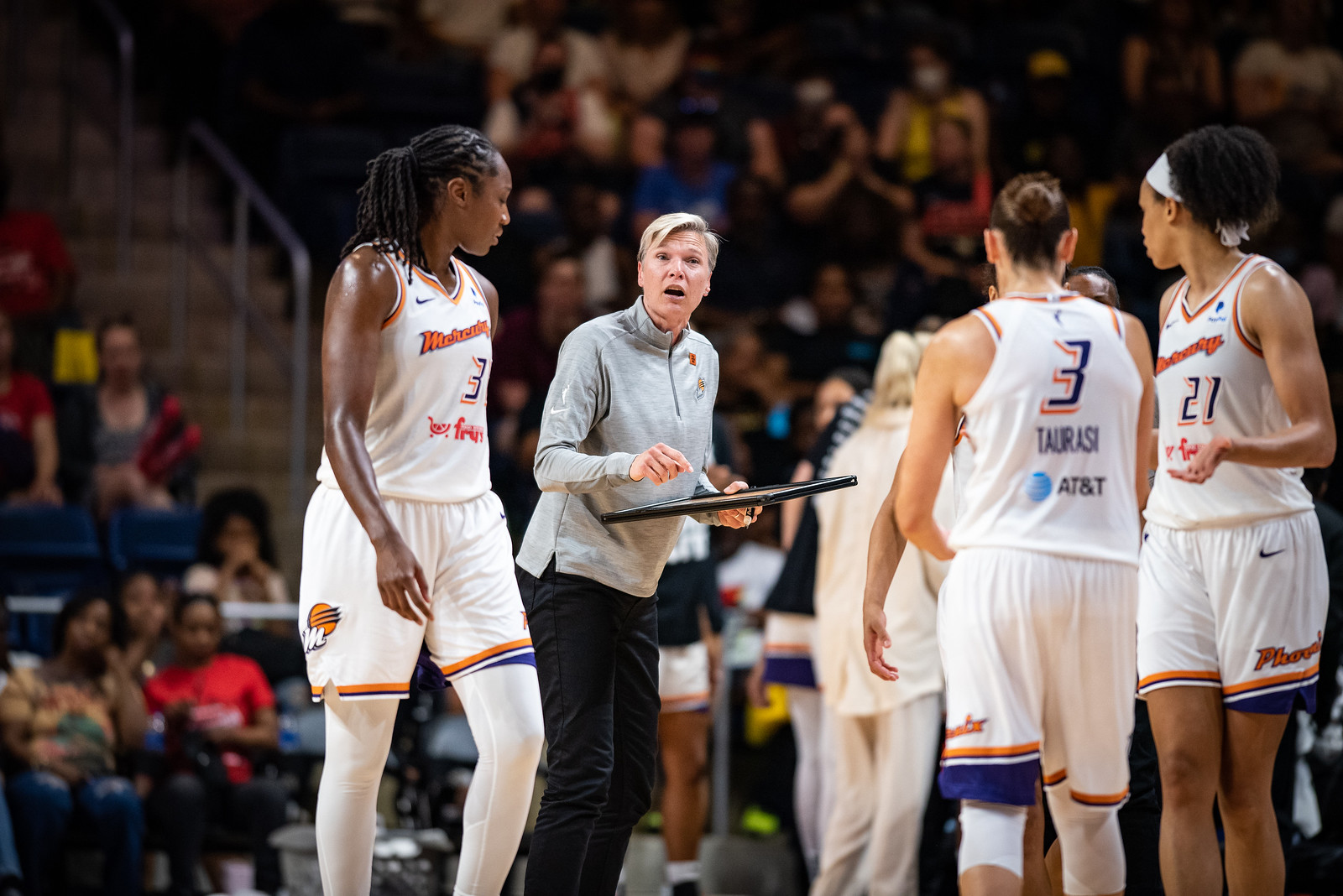 Phoenix head coach Vanessa Nygaard holds a clipboard while talking to Mercury players Tina Charles, Diana Taurasi, and Brianna Turner