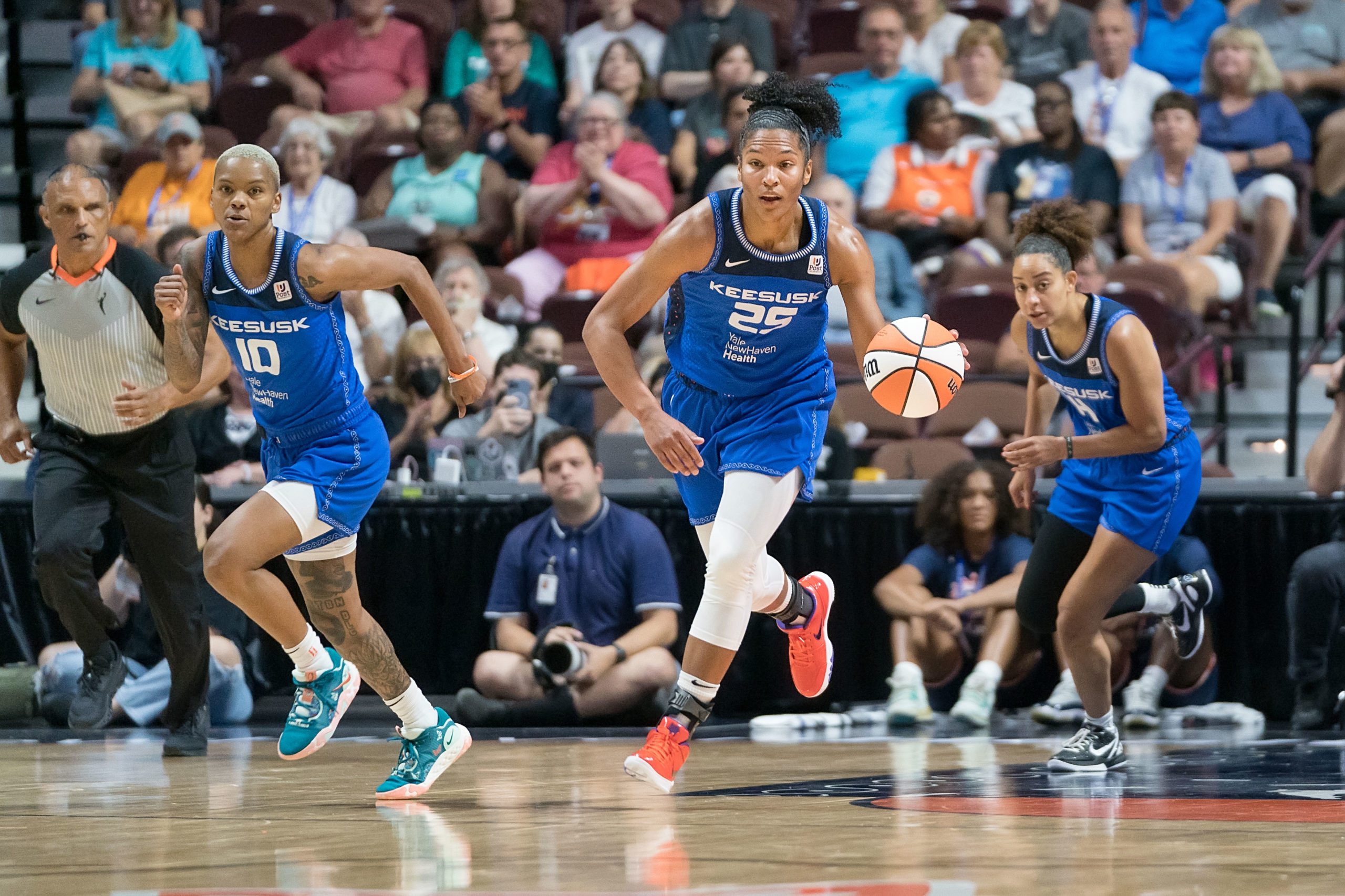 Connecticut Sun big wing Alyssa Thomas brings up the ball. Sun combo guard Courtney Williams and Sun point guard Bria Hartley run close behind Thomas.